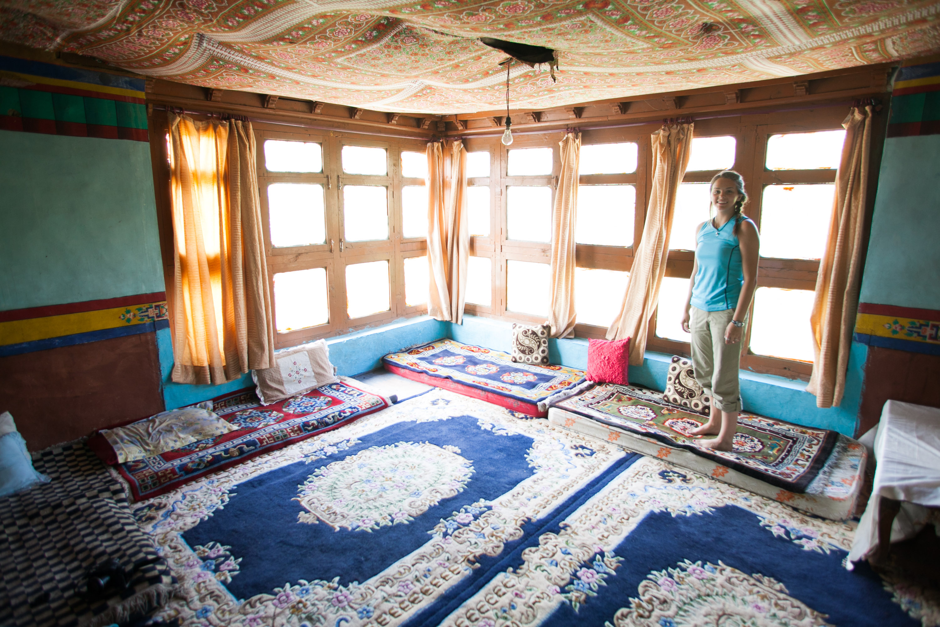 Students stand among patterned rugs and cushions in a decorated homestay room