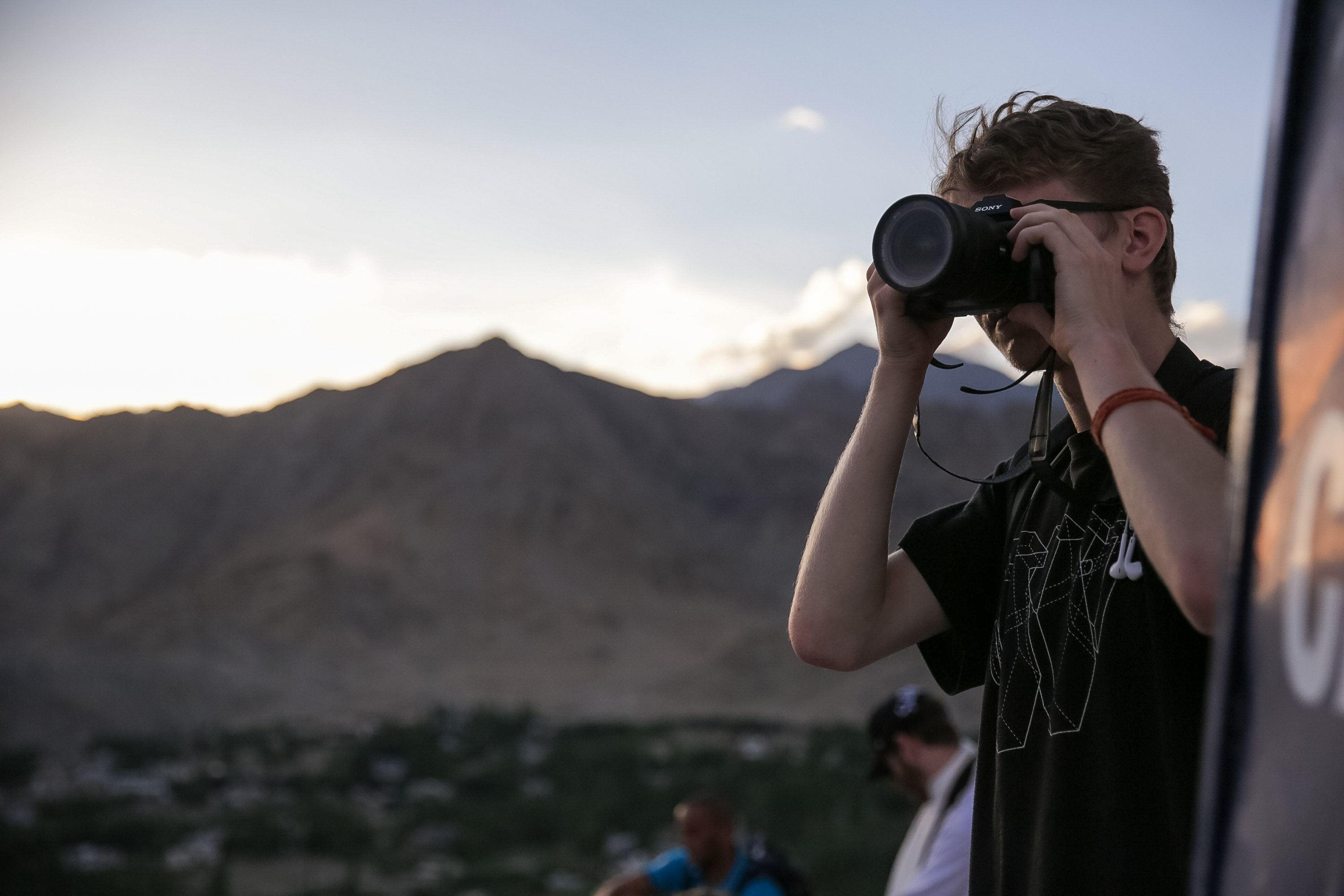 A student photographs the mountain view through a telephoto lens at dusk