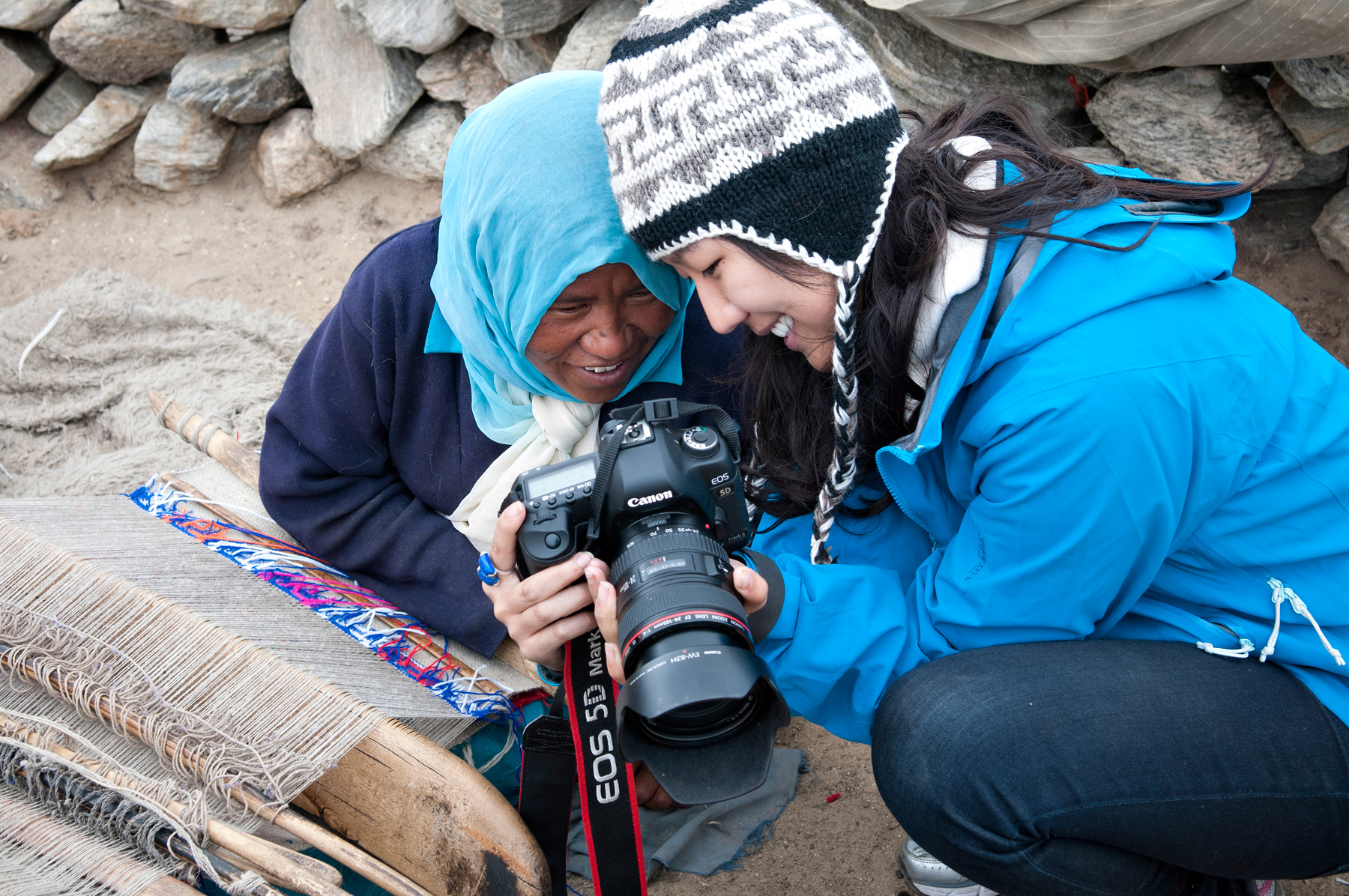 On a school trip, a student shows a local weaver a photo on her camera