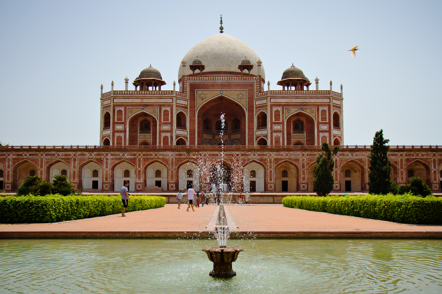 A fountain sprays in front of Humayun's Tomb under a clear sky