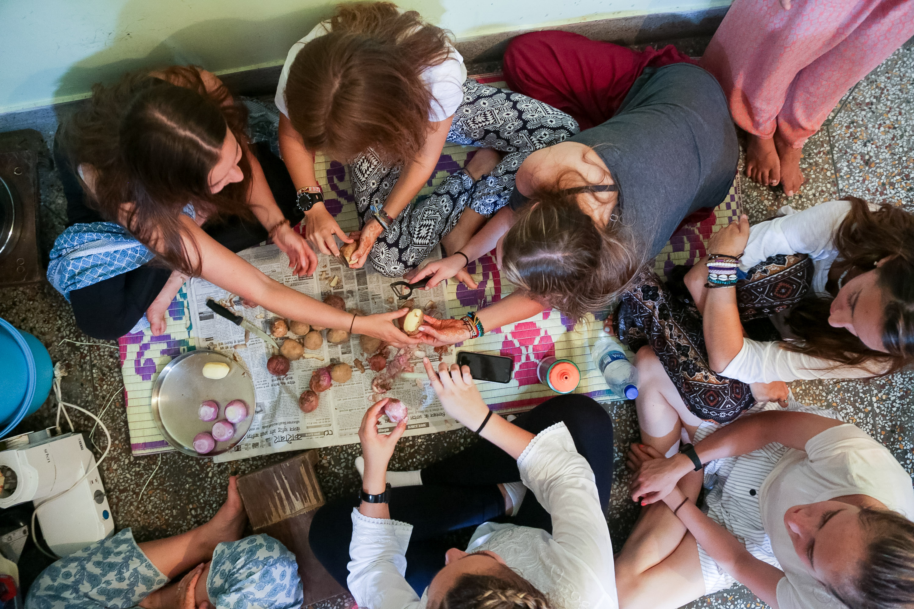 Students gather on the floor preparing food together, viewed from above