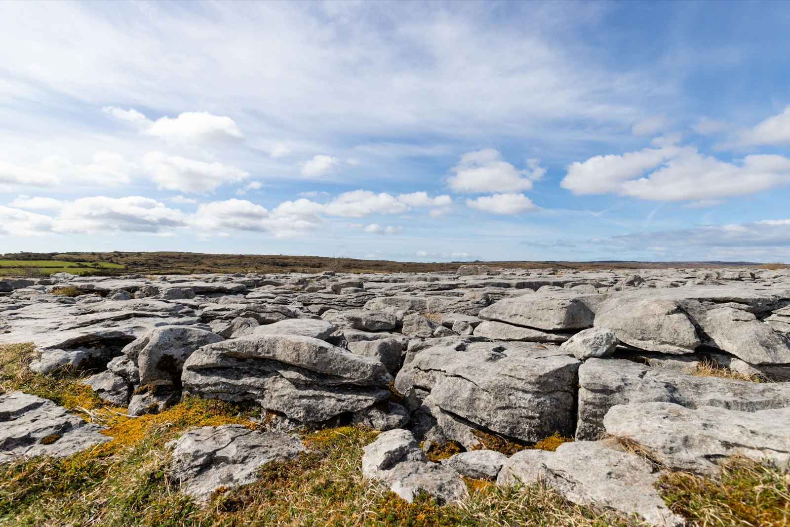Fissured grey limestone pavement stretches to a low horizon under broken cloud in Ireland