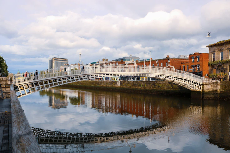 The white cast-iron arch of the Ha'penny Bridge spans the River Liffey in Dublin, Ireland