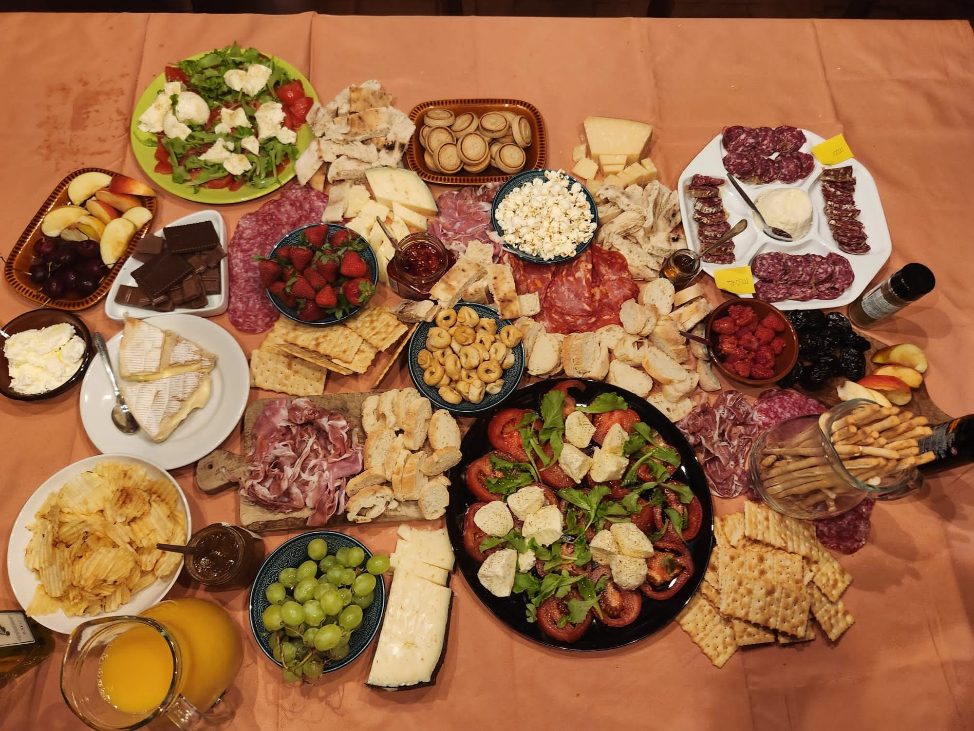 A table spread with cheeses, cured meats, salads, fruit and crackers for an Italian meal