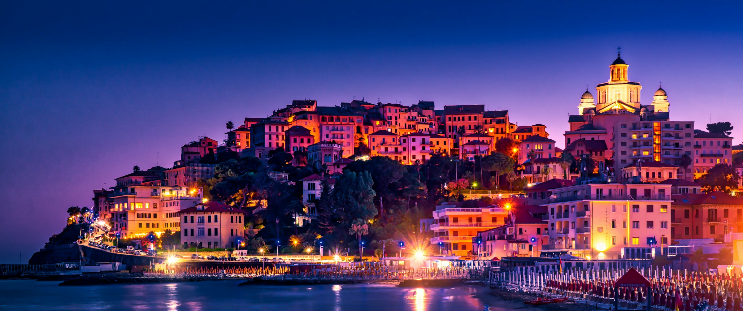 The hillside old town of Porto Maurizio in Imperia lit up at dusk above the Ligurian Sea