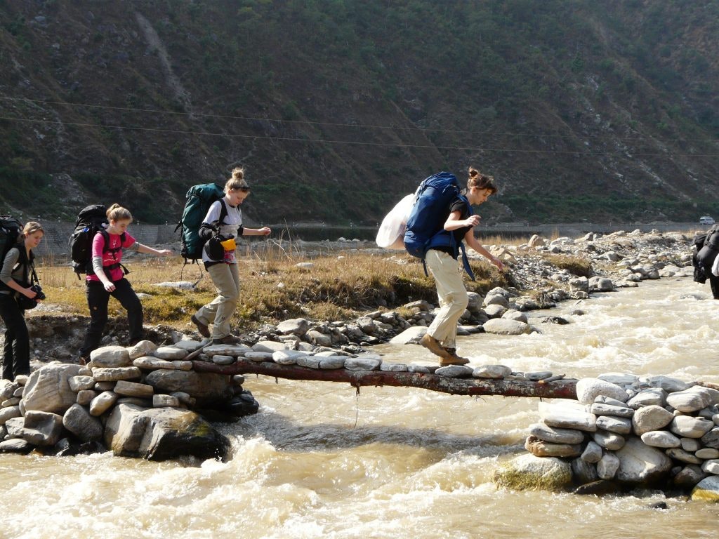 Rustic Pathway students pass a small stone bridge in Nepal