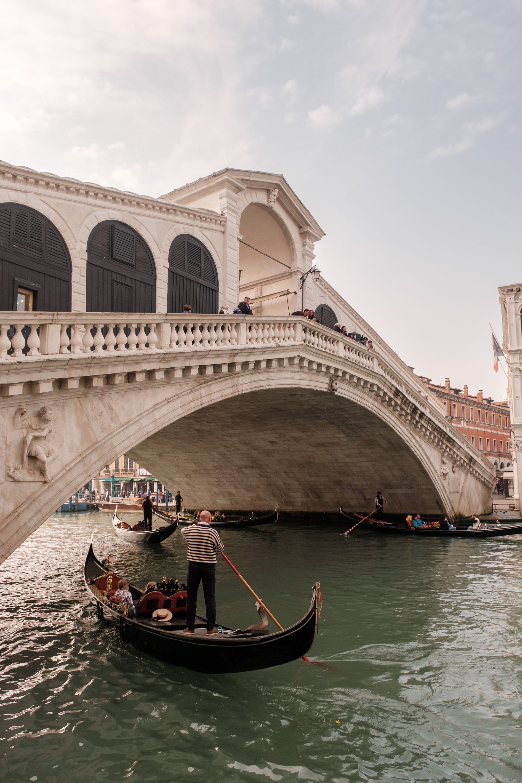 A gondolier steers a gondola beneath the Rialto Bridge in Venice