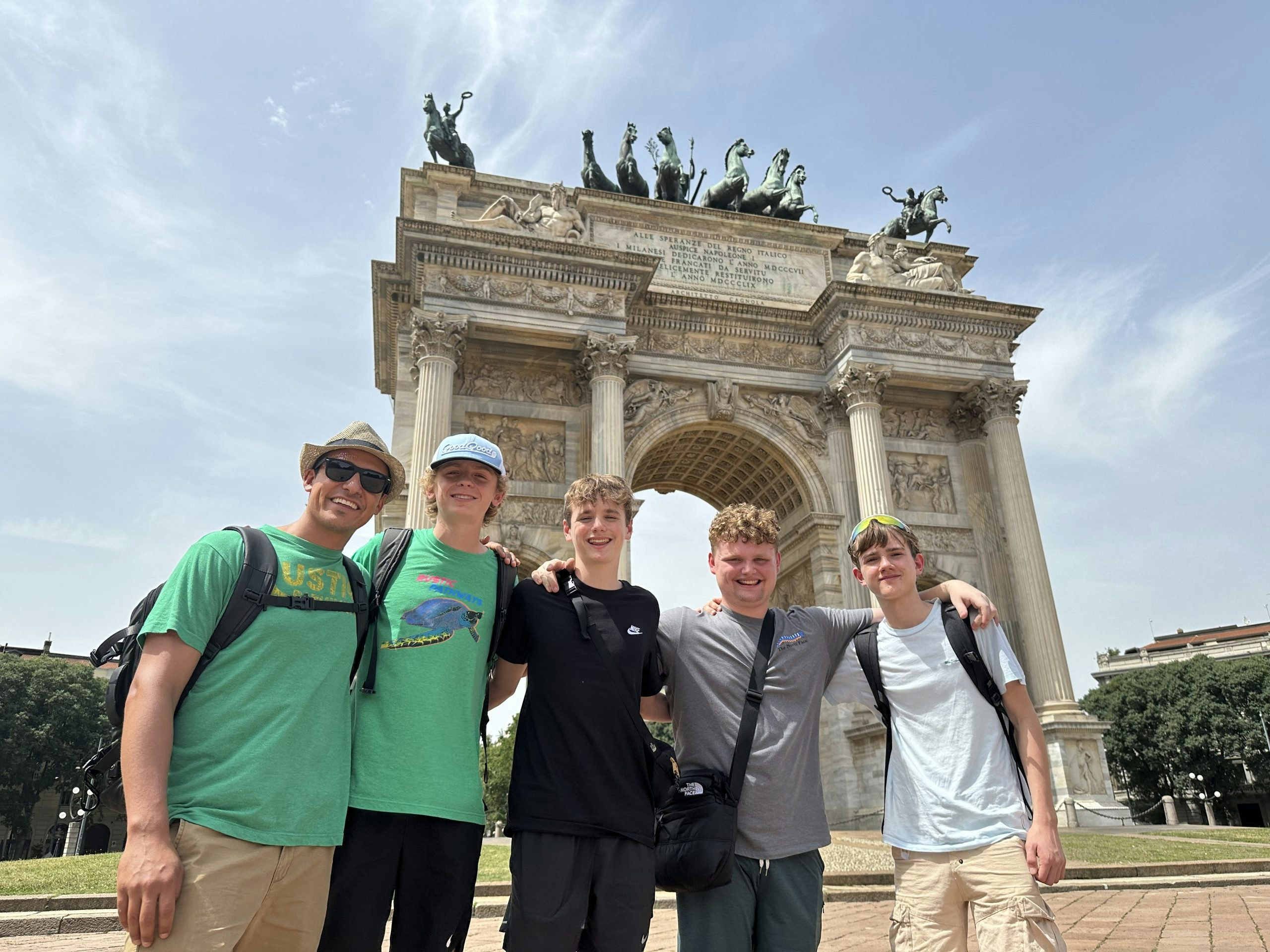 Group of male student travelers posing in front of the Porta Sempione in Italy.