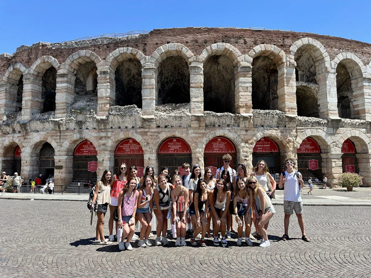 A Rustic Pathways group stands on the cobbled square in front of the Roman Arena in Verona, Italy