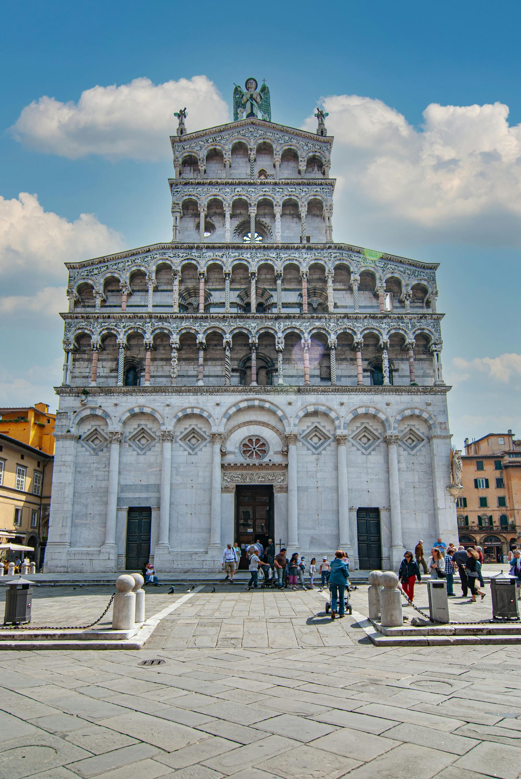 Ornate marble facade of an Italian cathedral with tiered arcades against a blue sky