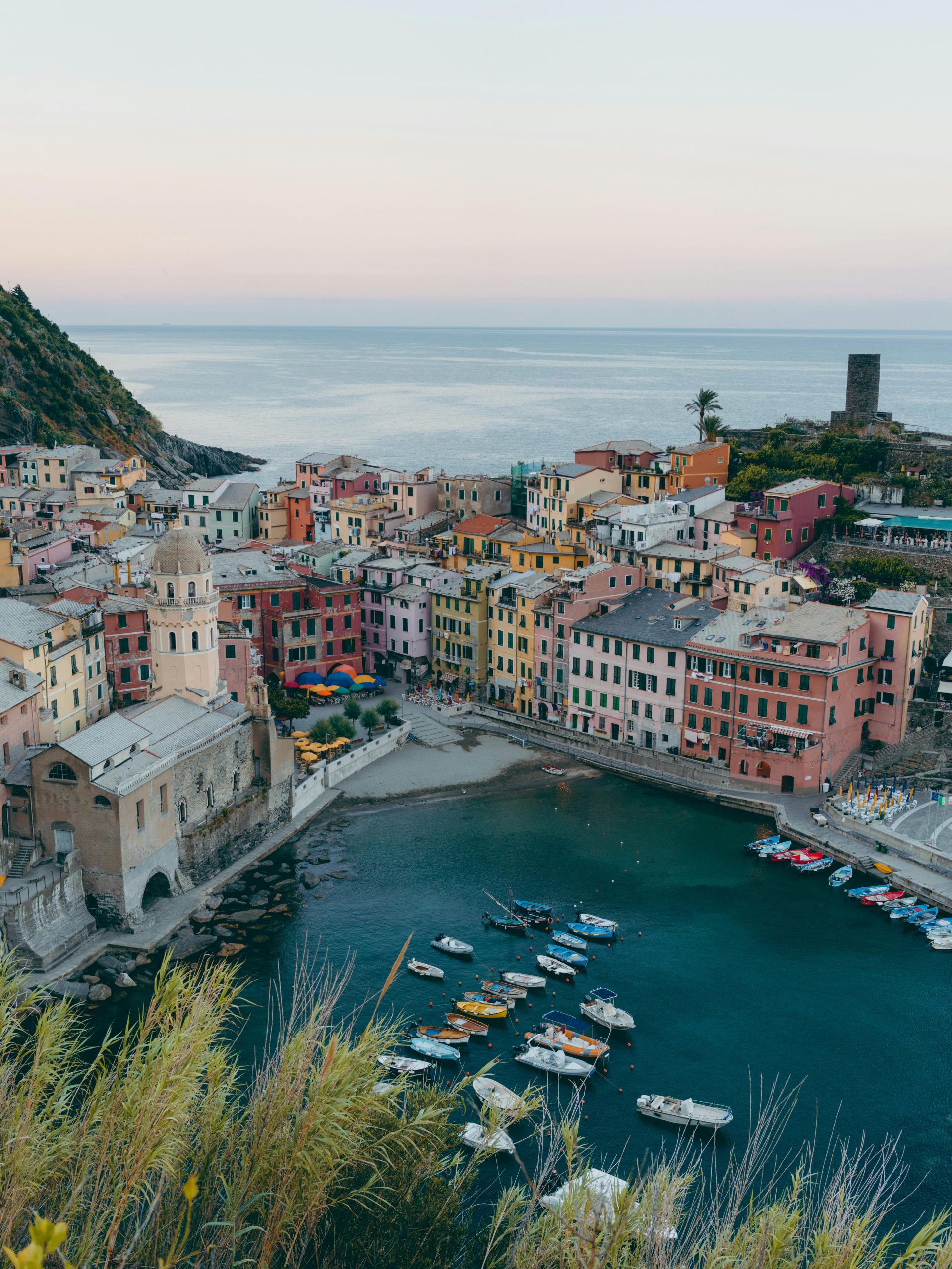 Colorful cliffside village overlooks a small harbor filled with boats in Cinque Terre