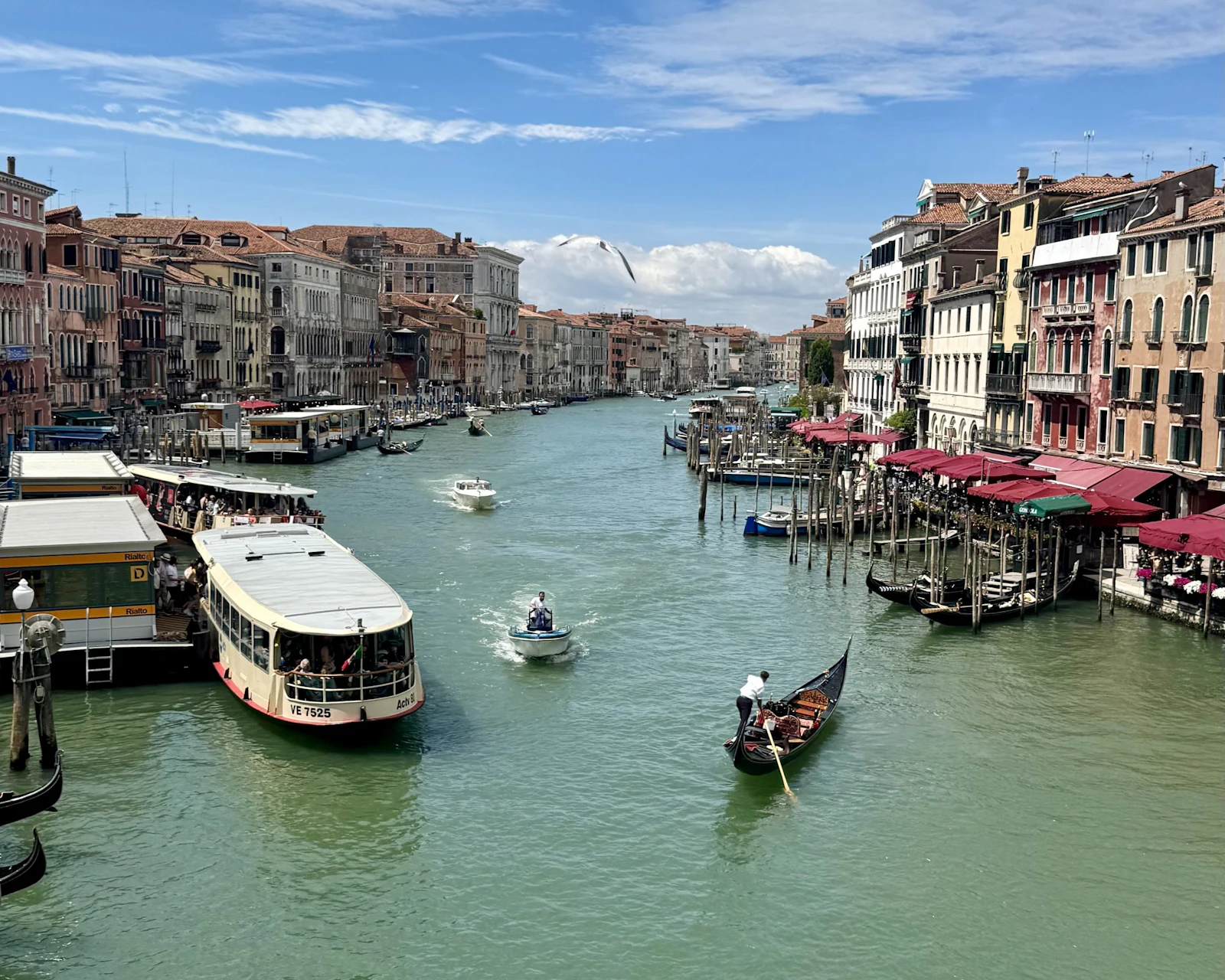 Water buses, motorboats and a gondola move along the Grand Canal in Venice, Italy, between rows of colorful palazzos