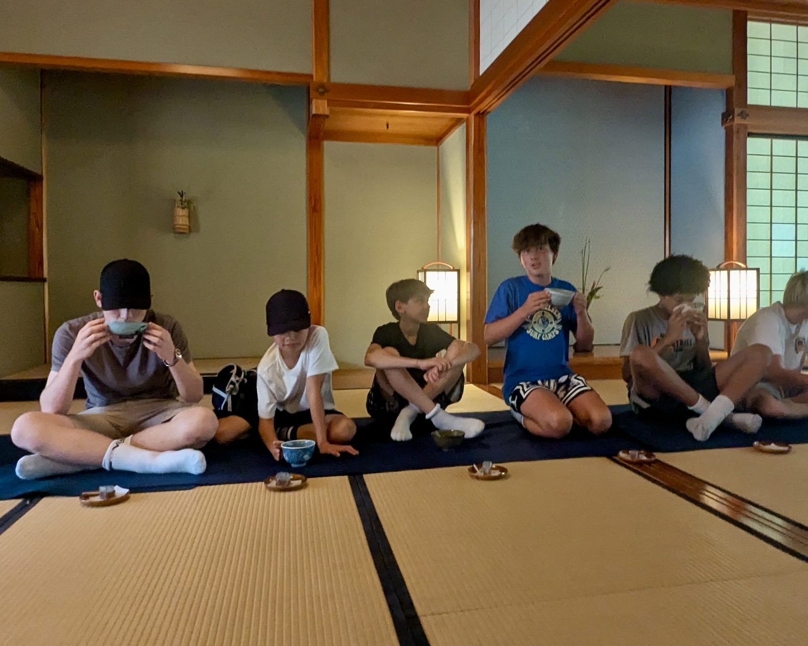 Students sit on tatami and drink matcha from bowls during a tea service