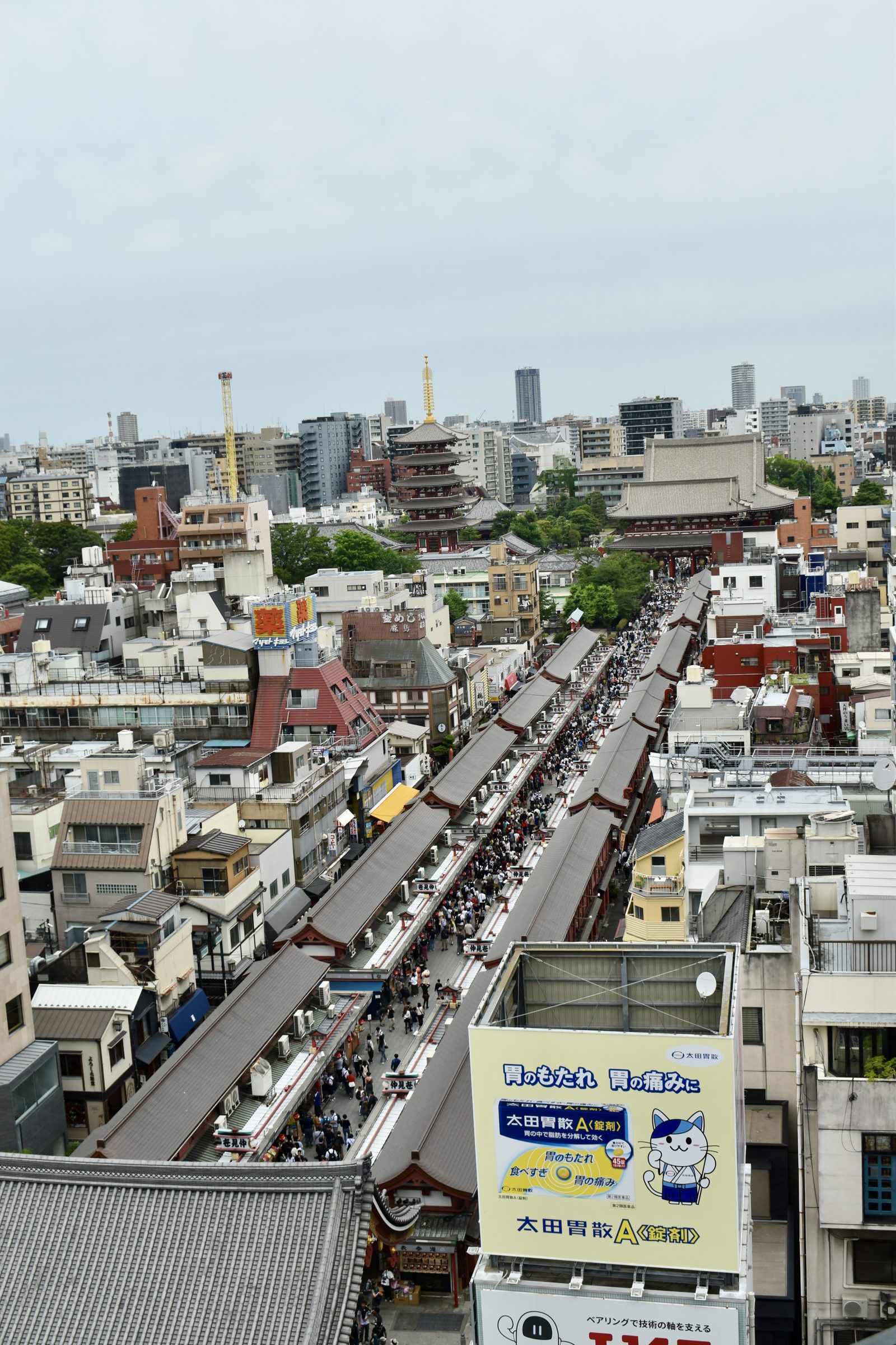 Nakamise-dōri stretches toward Sensō-ji and its five-storied pagoda, seen from above over Asakusa rooftops