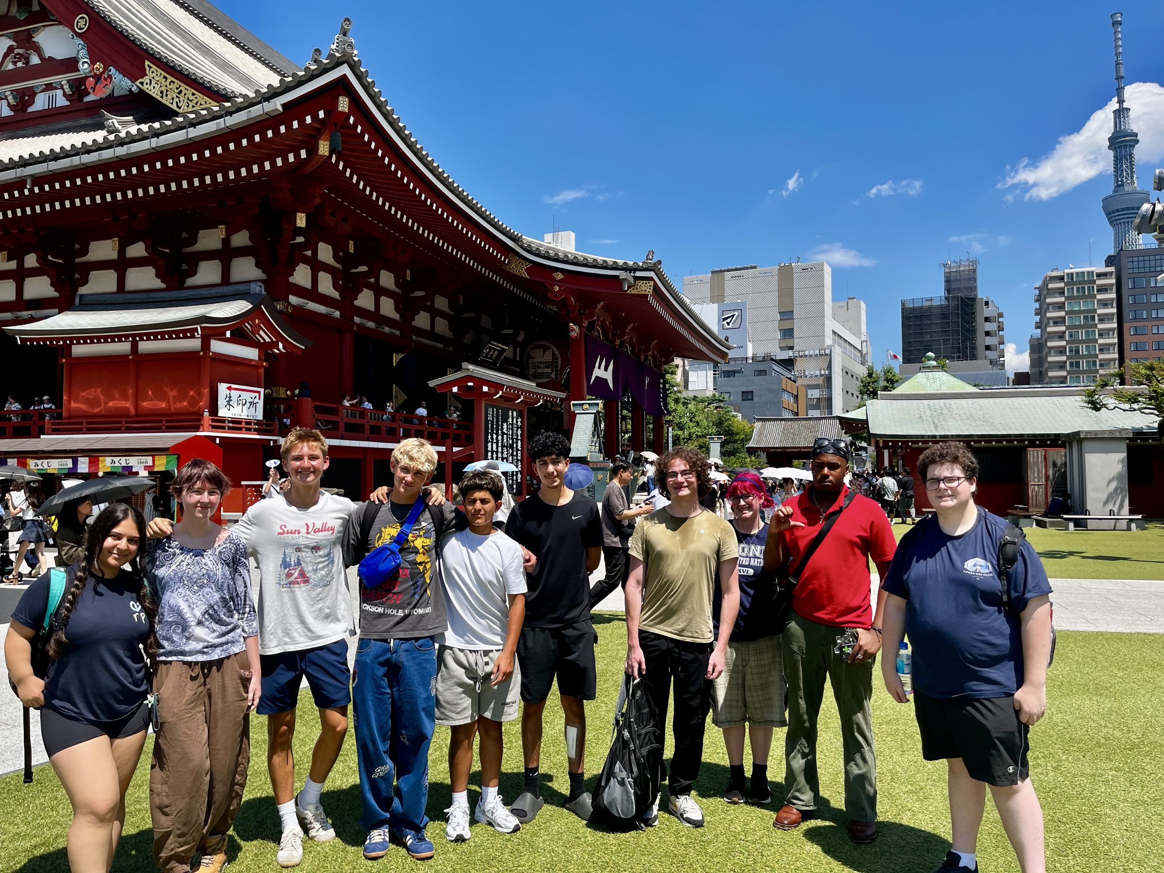 Students stand together outside Sensō-ji, with Tokyo Skytree rising behind the temple roofs