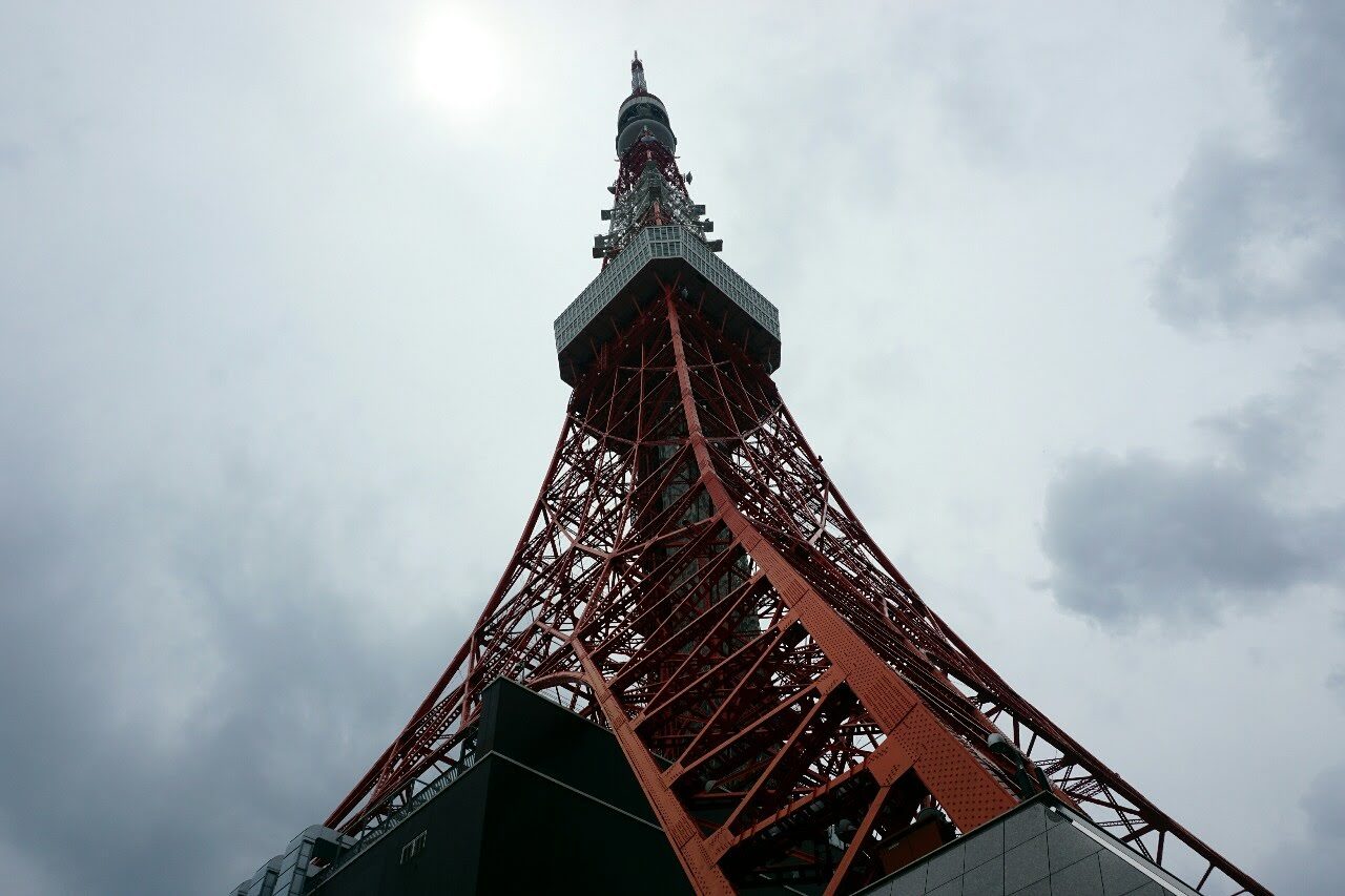 Tokyo Tower&rsquo;s orange lattice rises into a bright overcast sky