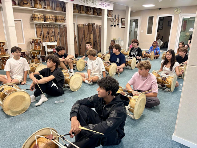 Students sit on the floor with janggu drums and sticks during a samulnori class in Seoul