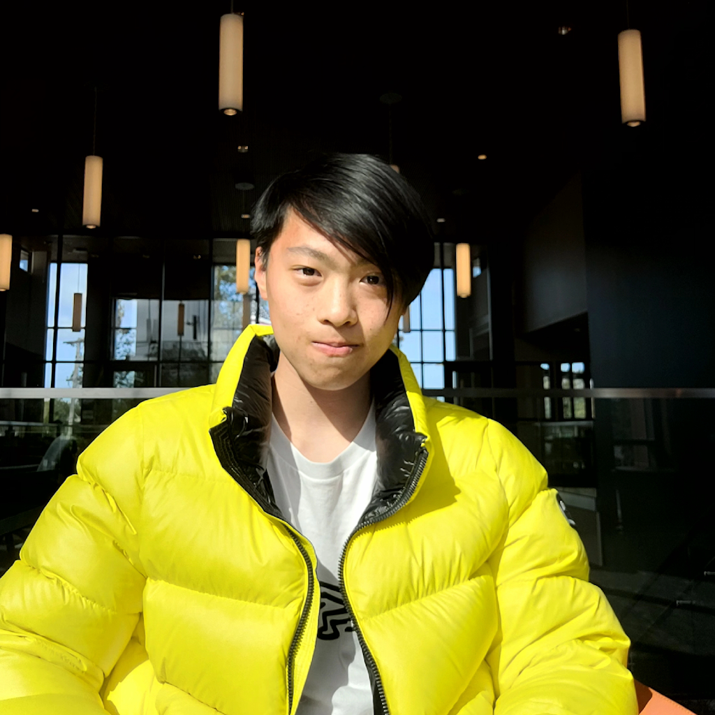 Portrait of Jayden Wan in a bright yellow jacket, sitting in a sunlit room.