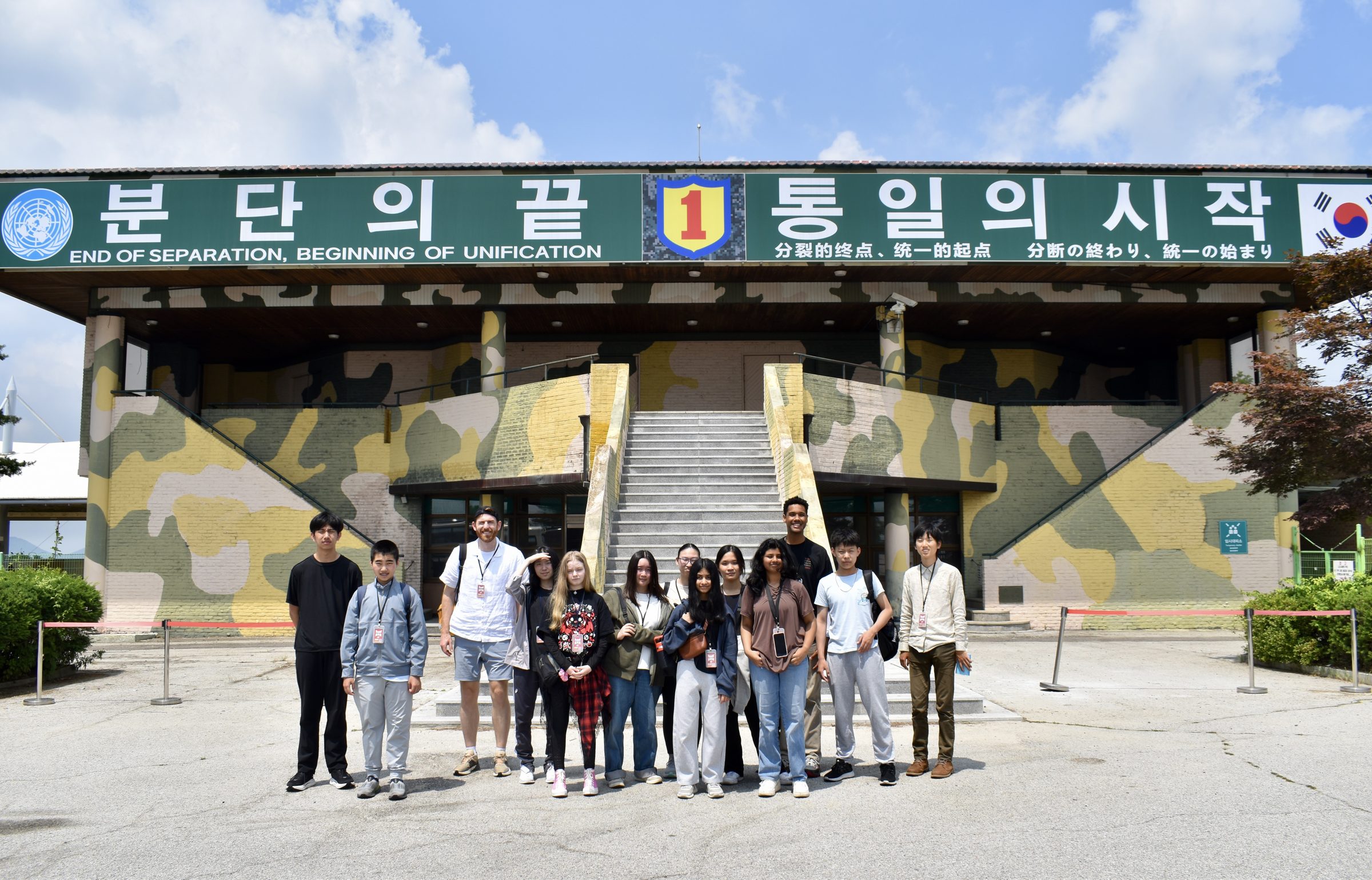 A school group in front of the DMZ observatory at Imjingak, under a banner reading End of Separation, Beginning of Unification