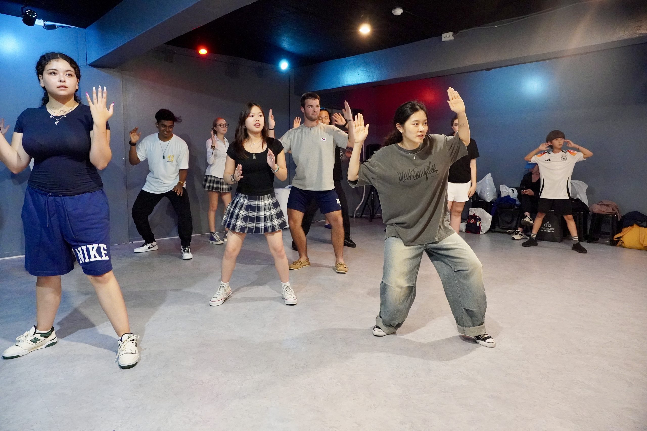 Students take a K-pop dance class in a professional Seoul studio, following choreography with focus and energy.