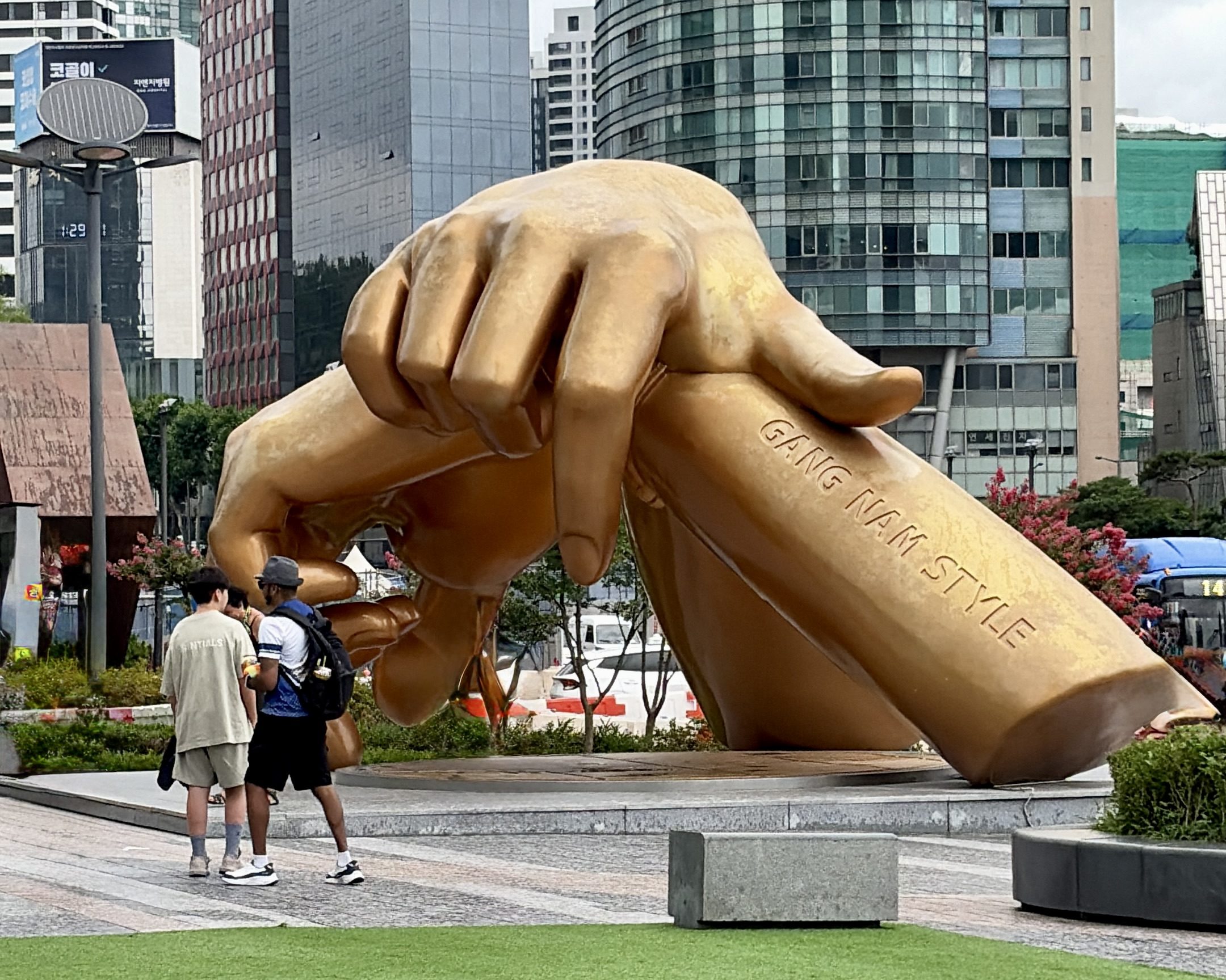 The Gangnam Style hands sculpture outside COEX, students passing beneath it