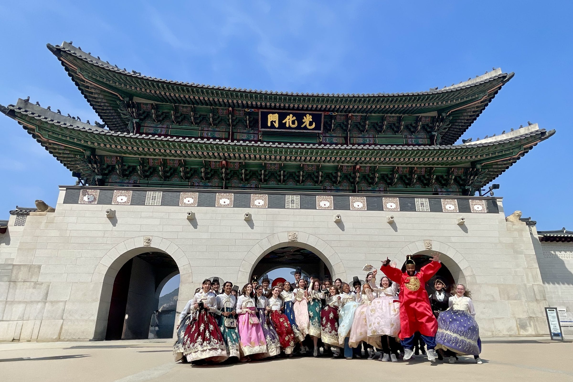 A school group in hanbok gathers in front of the Gyeongbokgung Palace gate