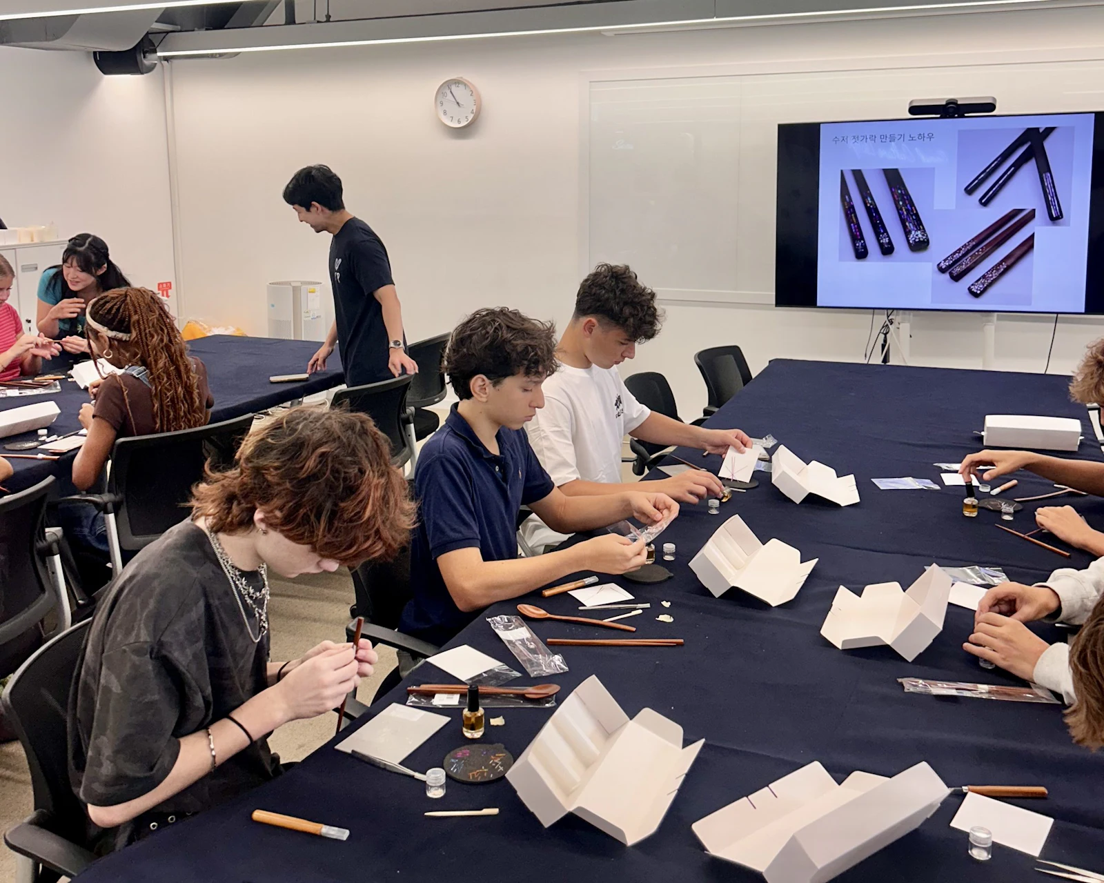 Students work on craft pieces at a long table during a workshop in Seoul