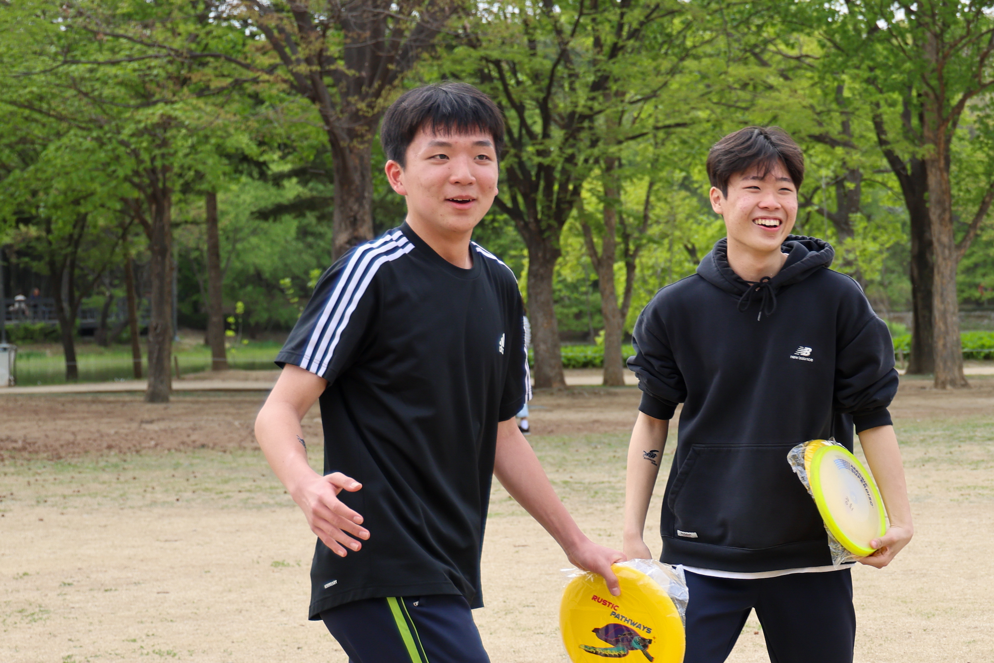 Student travelers laugh while holding frisbees in a park