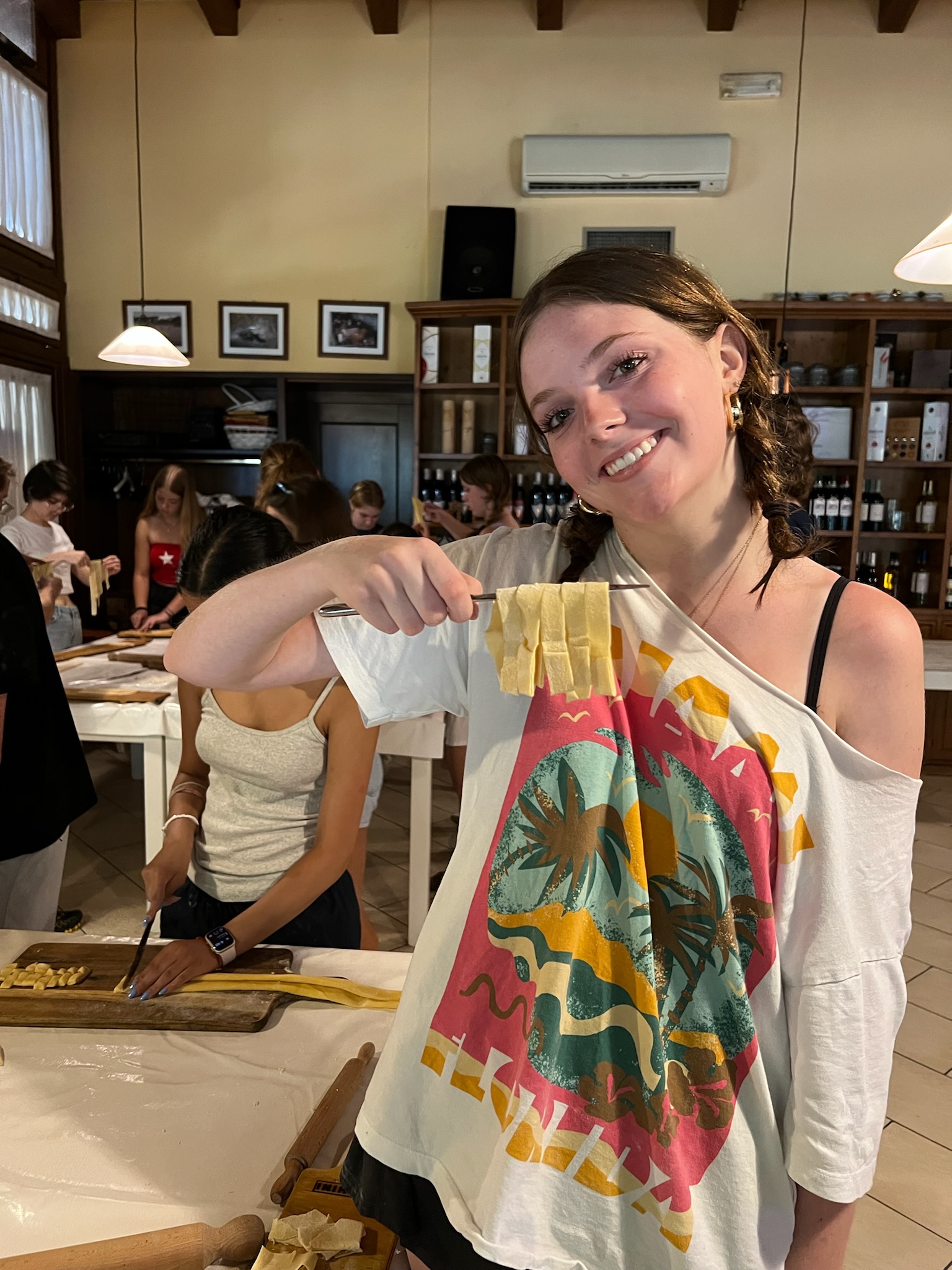 A student holds up a strip of fresh pasta during a pasta making workshop