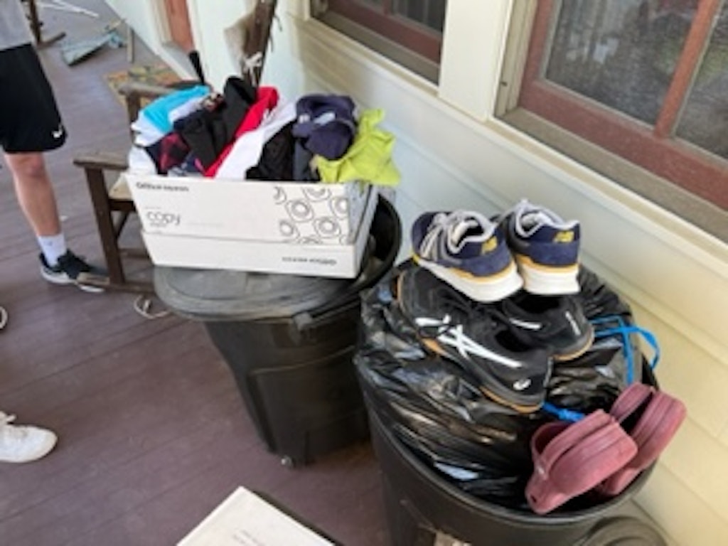 Box filled with used clothing like shoes and shirts. 
