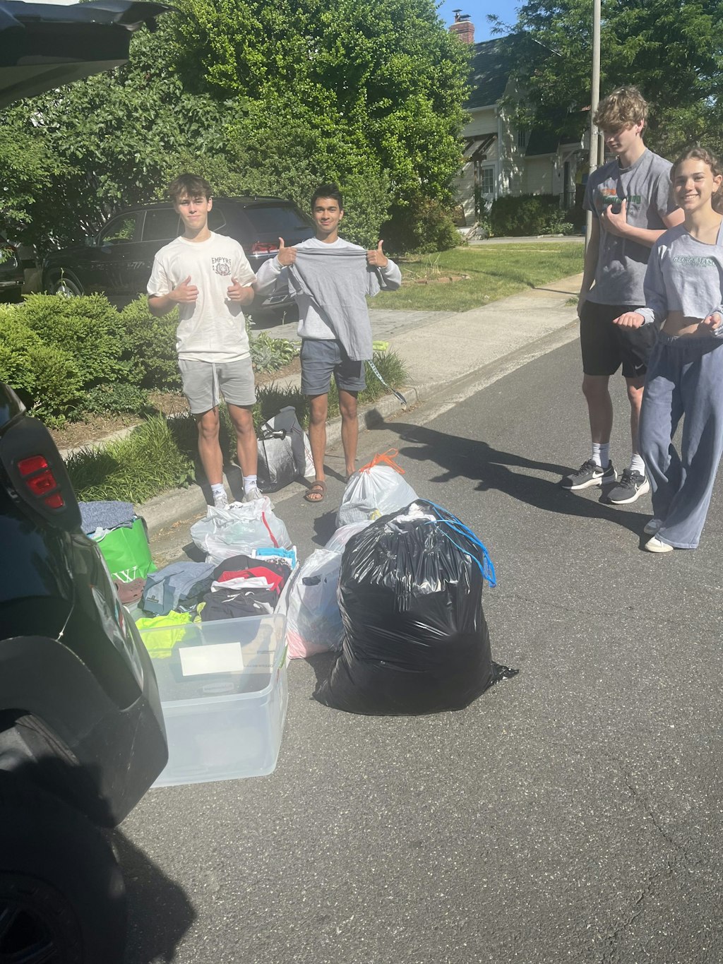 Group of high school students standing around boxes and bags of clothing donations. 