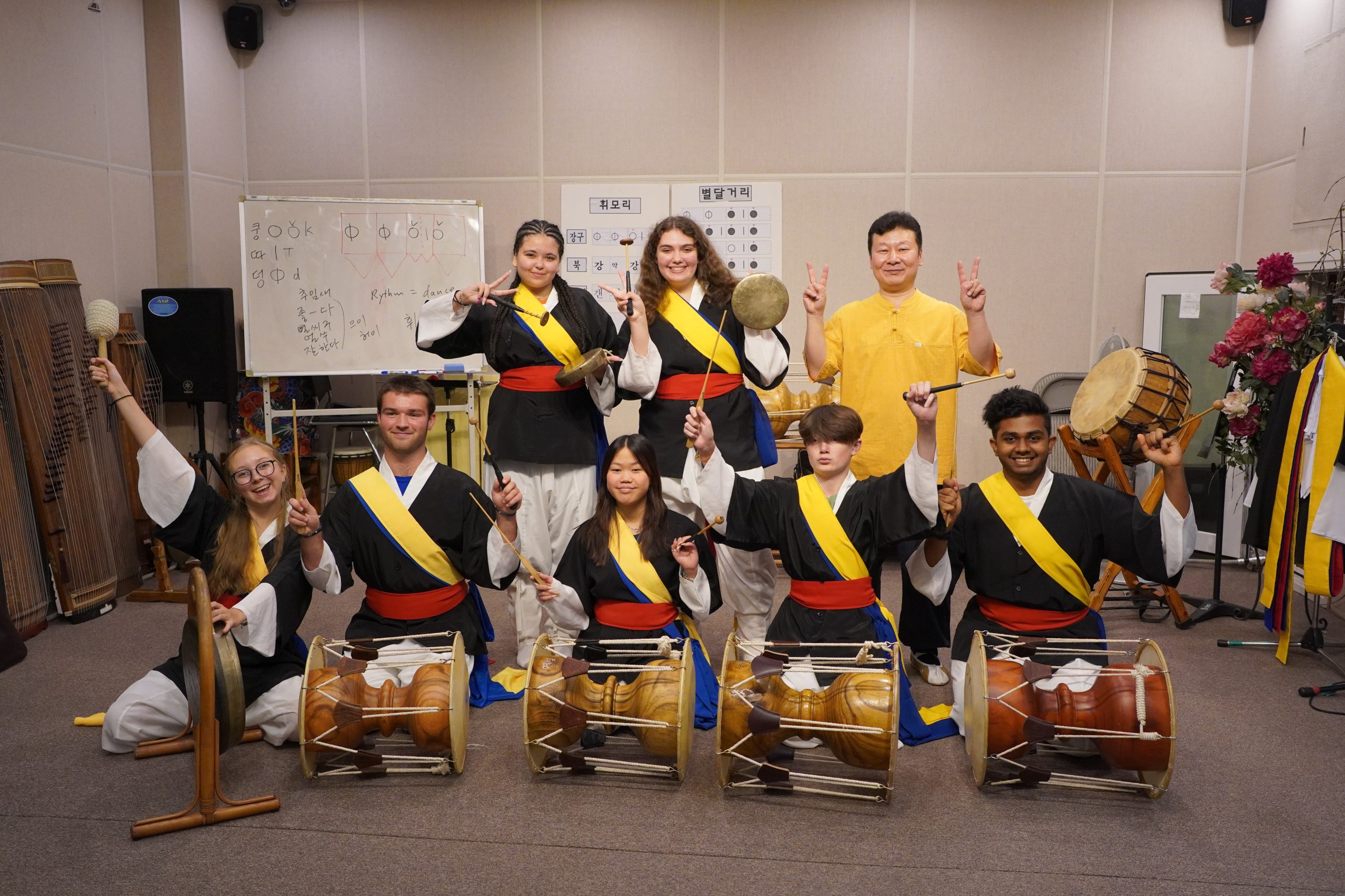 Group of student travelers posing for a photo with traditional Korean instruments.