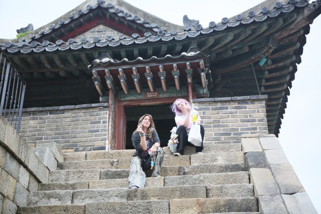 Student travelers posing on stairs under a traditional Korean building during a Korea teen tour.