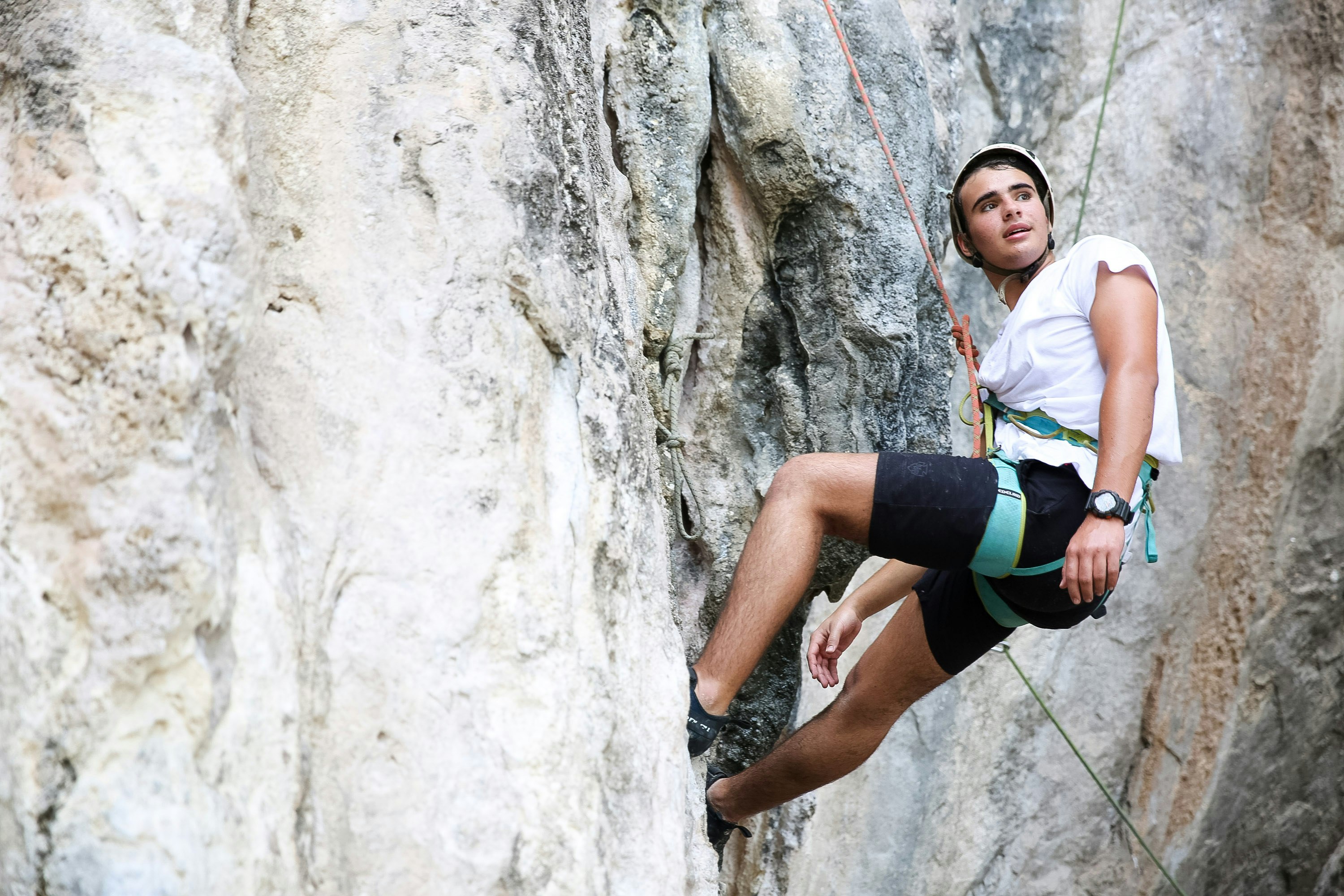 A student hanging from a wall while rock climbing in Laos.