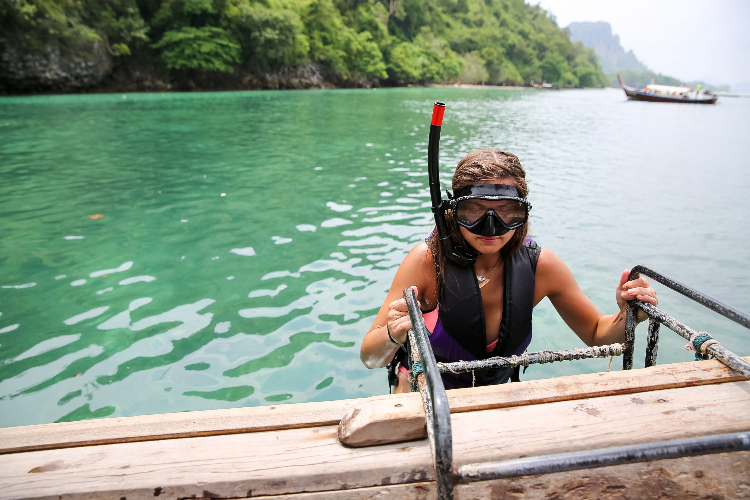 Girl wearing snorkeling gear getting out of the water.