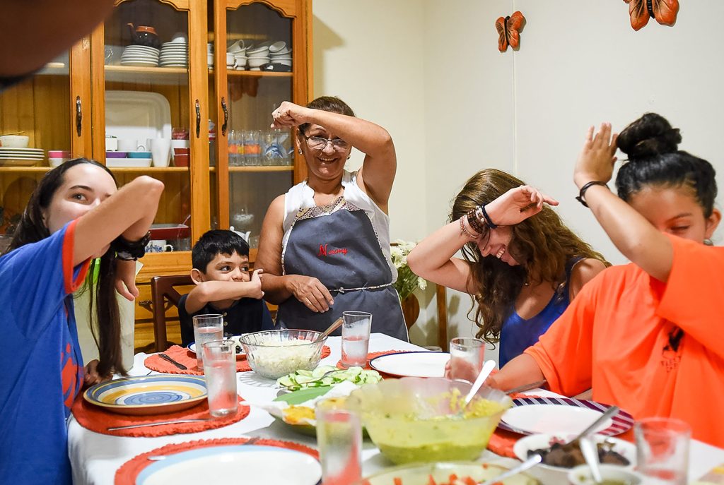 Language students play games around the dinner table with their homestay host family in the Dominican Republic.