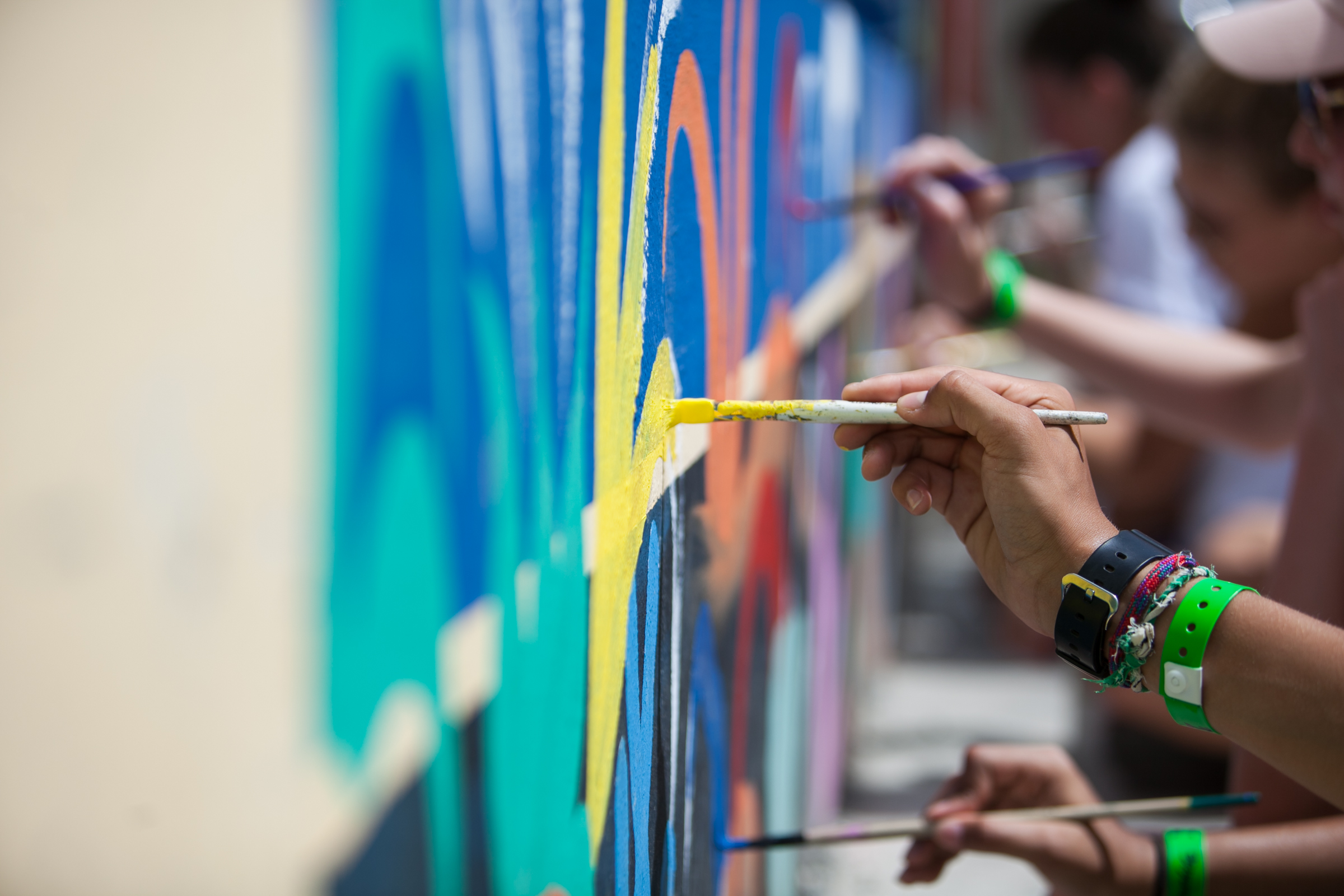 Students painting a colorful community mural as part of a volunteer abroad program, representing different volunteer abroad program types focused on community service and cultural exchange.