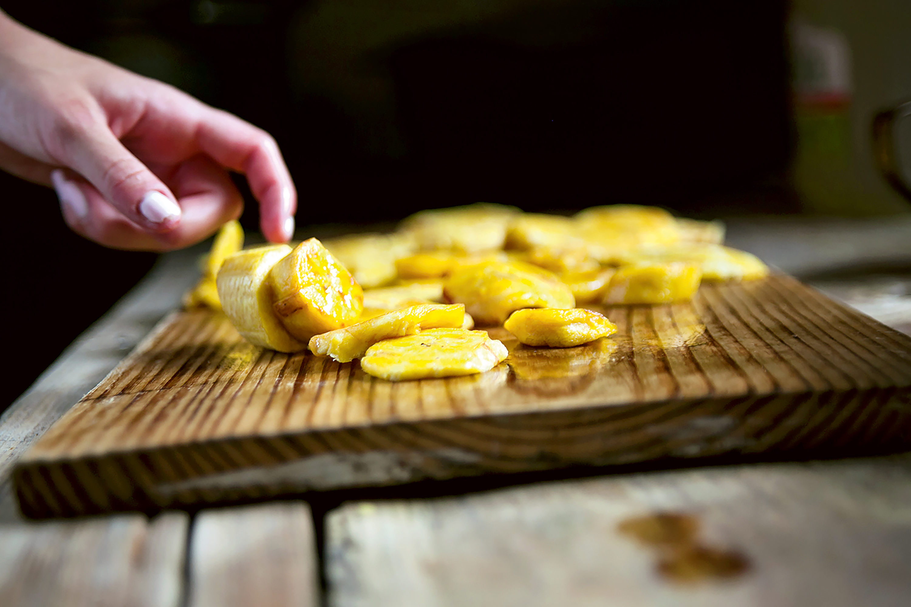 Student travelers arrange sliced plantains on a wooden cutting board