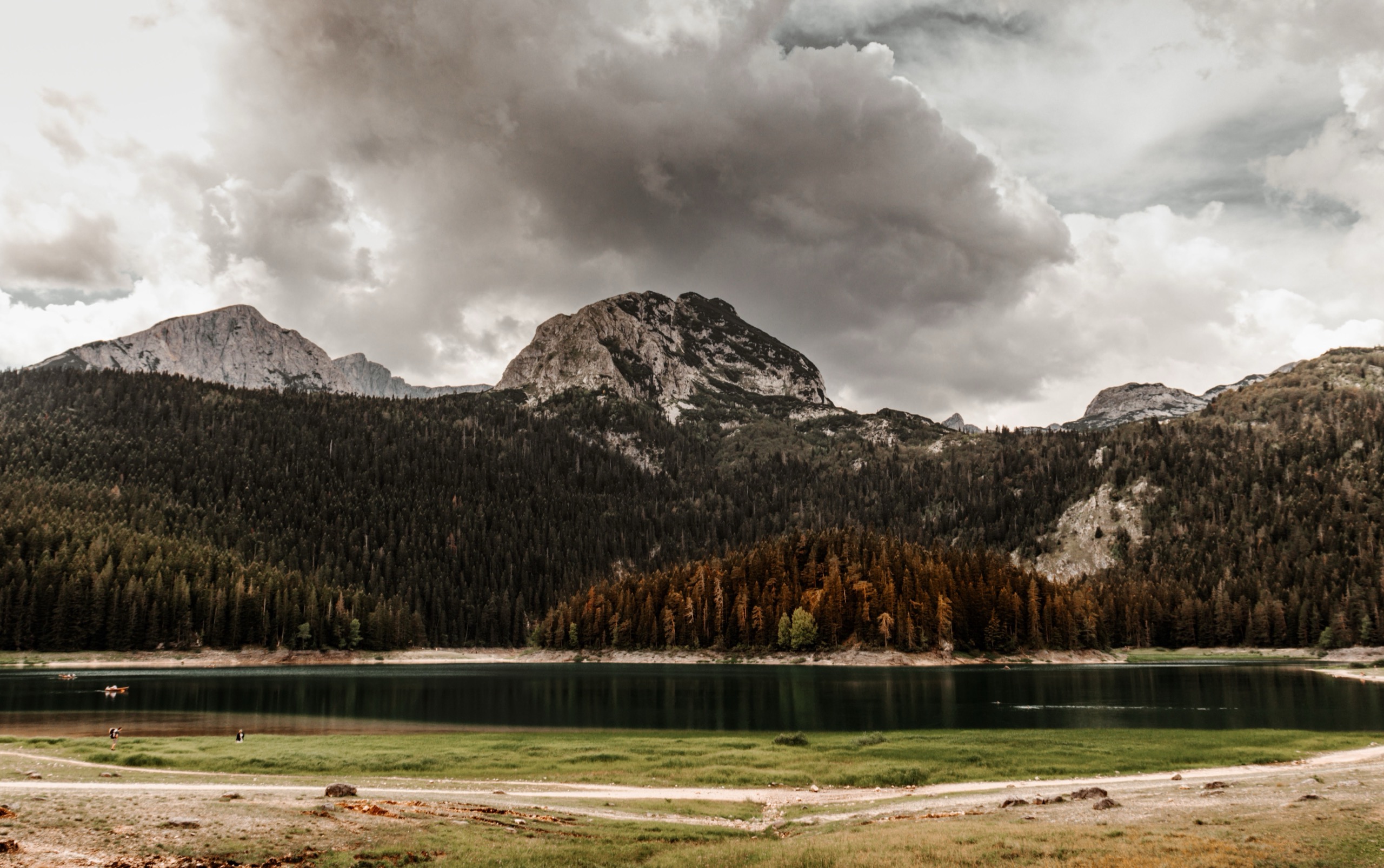 A glacial mountain lake reflecting surrounding peaks and forest in still water.