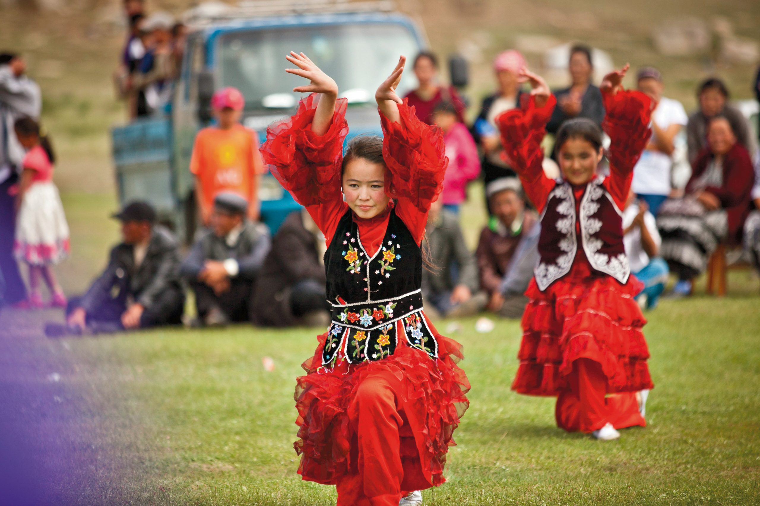Young dancers in red costume perform a traditional Mongolian dance for a visiting group.