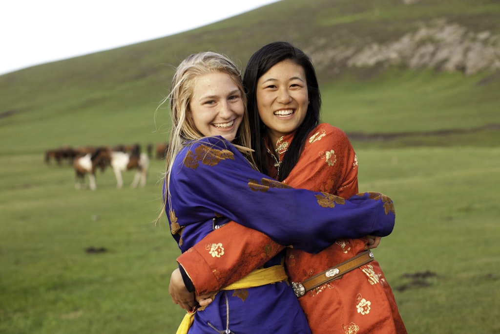 Two students embracing in traditional Mongolian attire during a Rustic Pathways volunteer abroad program, symbolizing friendship and the cultural benefits of volunteering abroad.