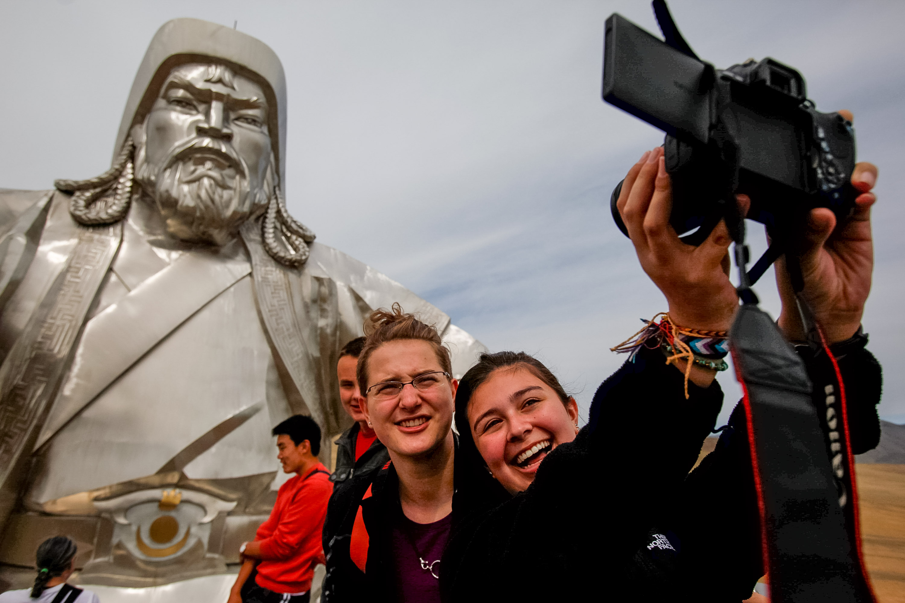 Students smile for a selfie beneath the giant Genghis Khan statue
