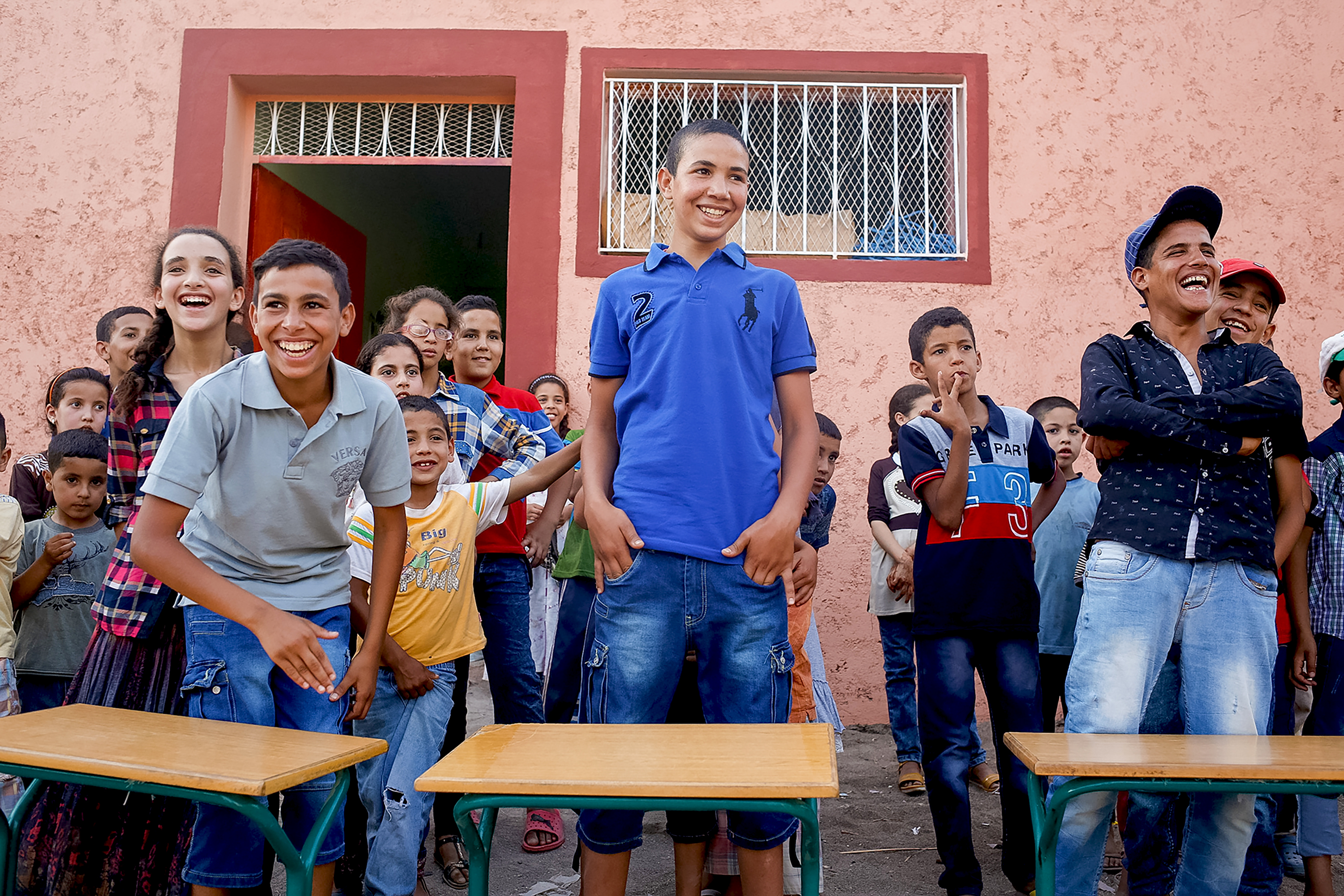 Teens laugh together outside a village building during a game