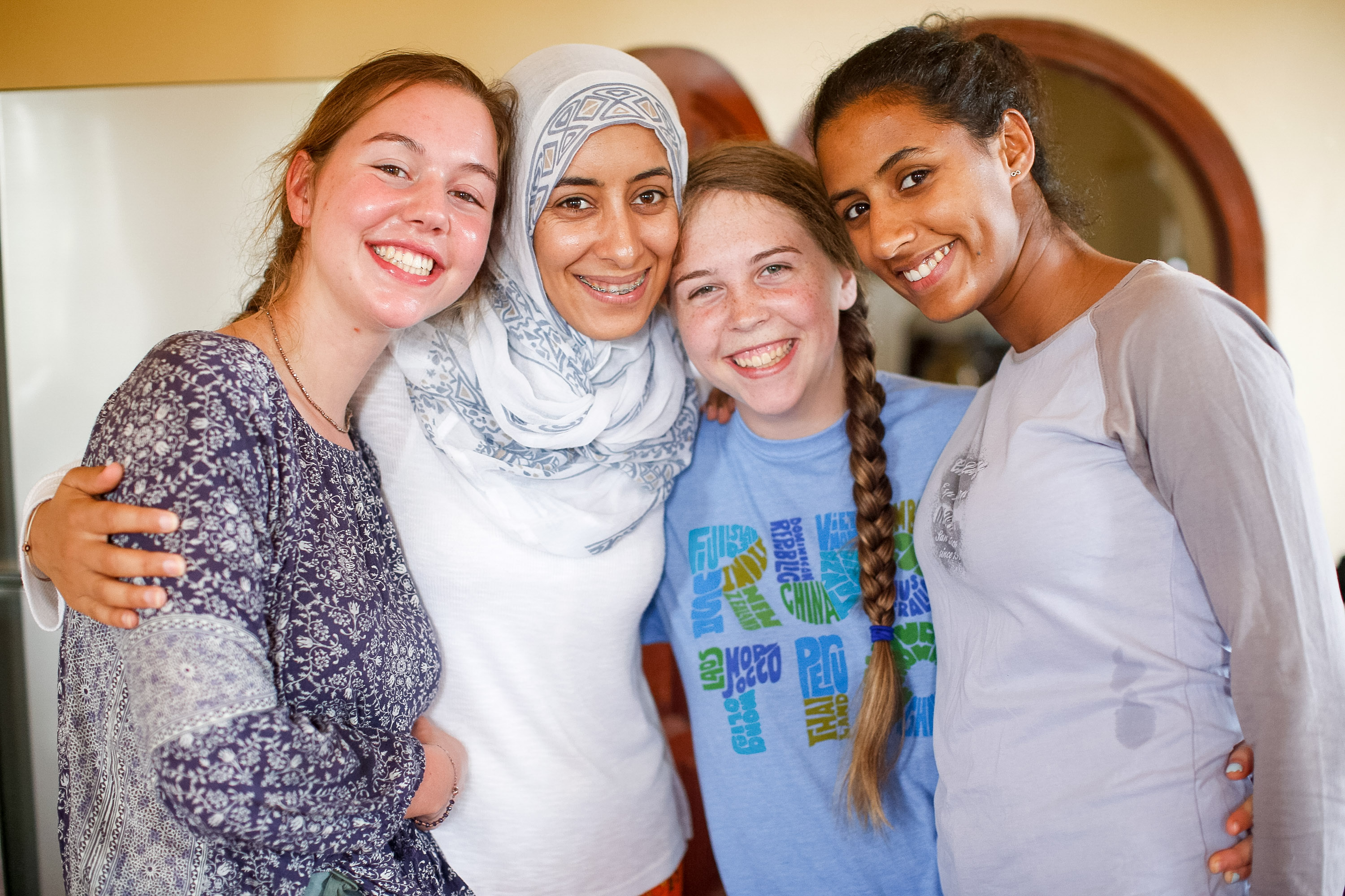 Students smile with arms around each other indoors