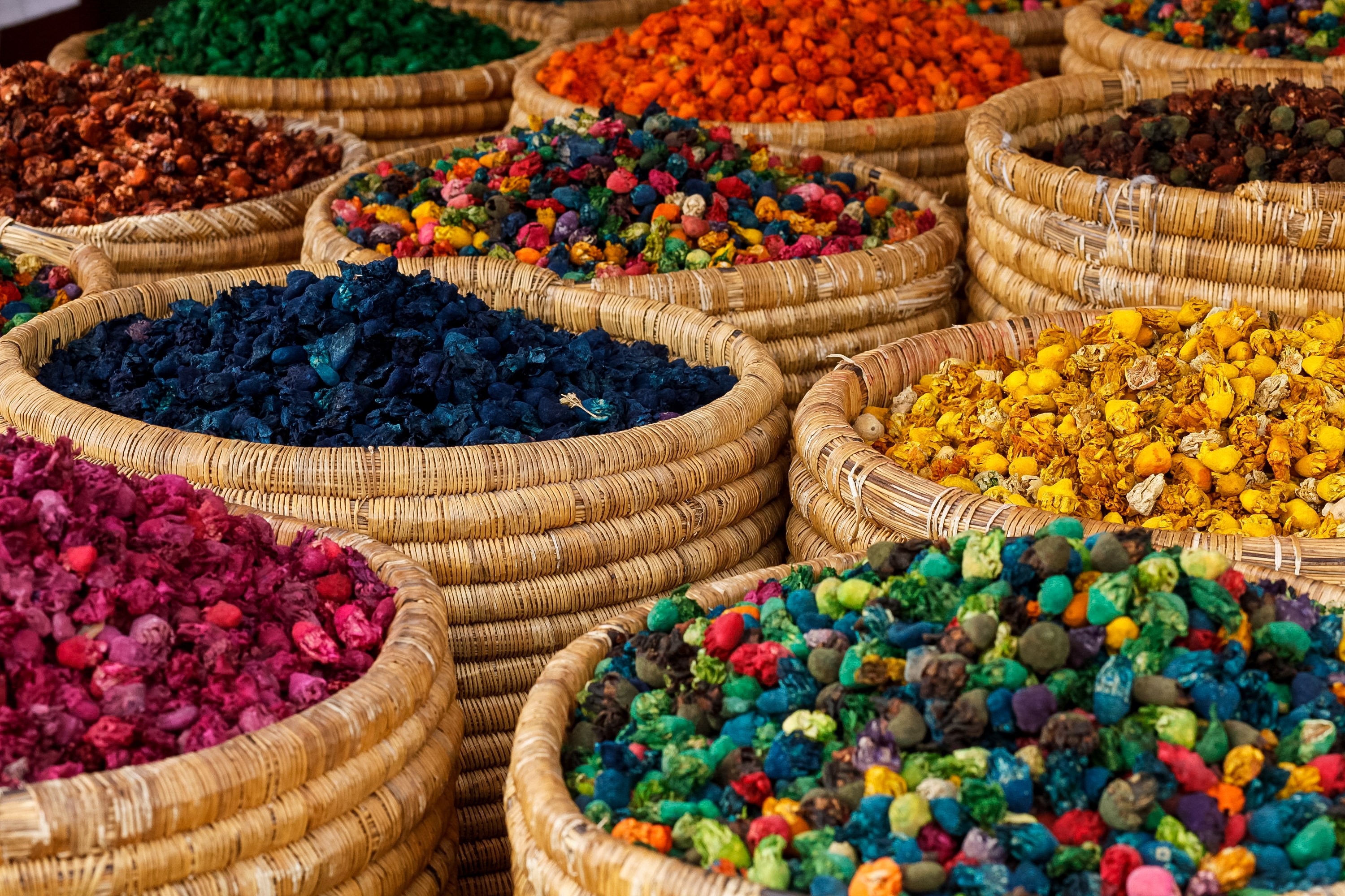 Woven baskets filled with colorful dried flowers and herbs at a Moroccan market stall