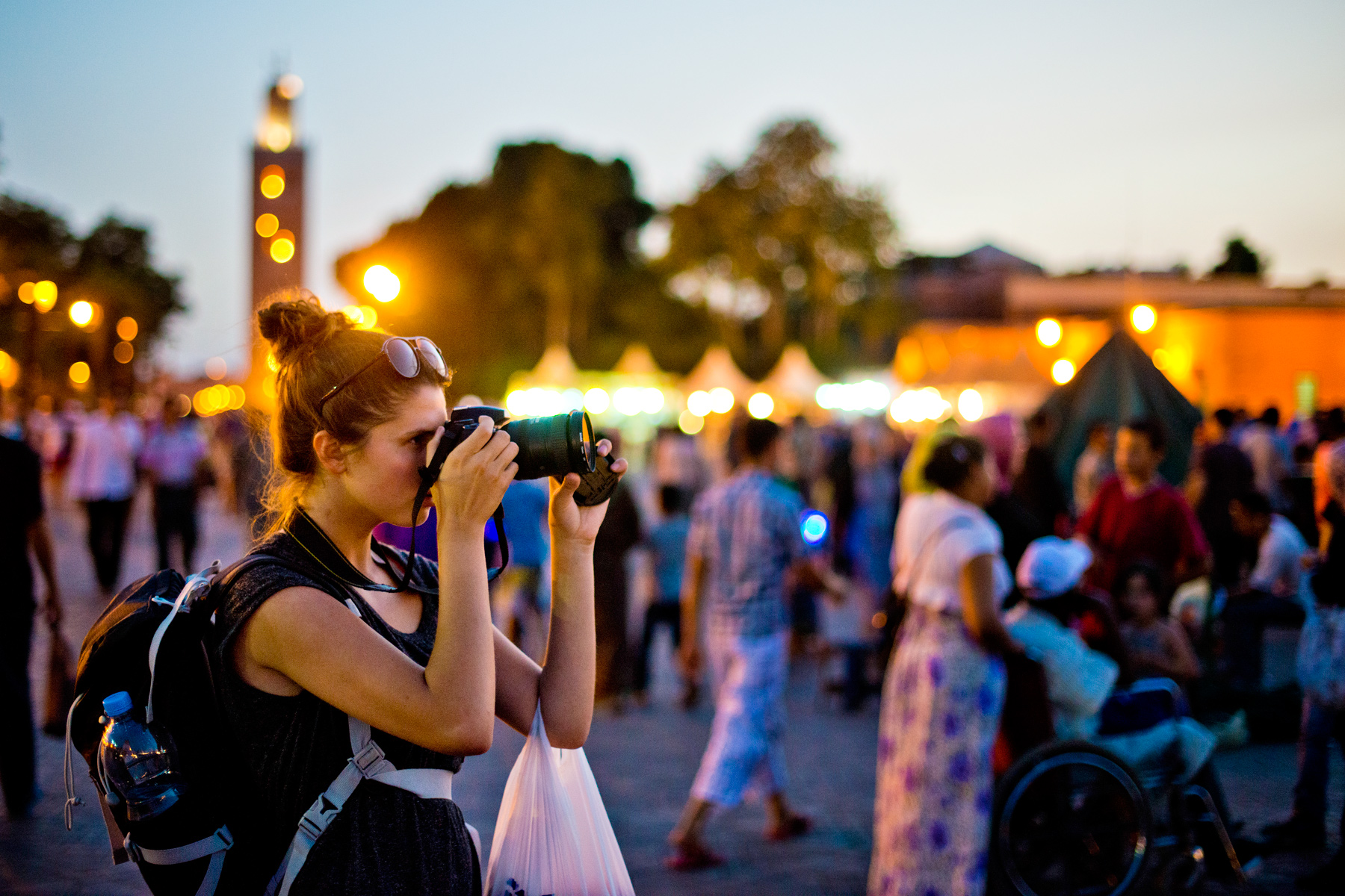 A student photographs a bustling market square at dusk