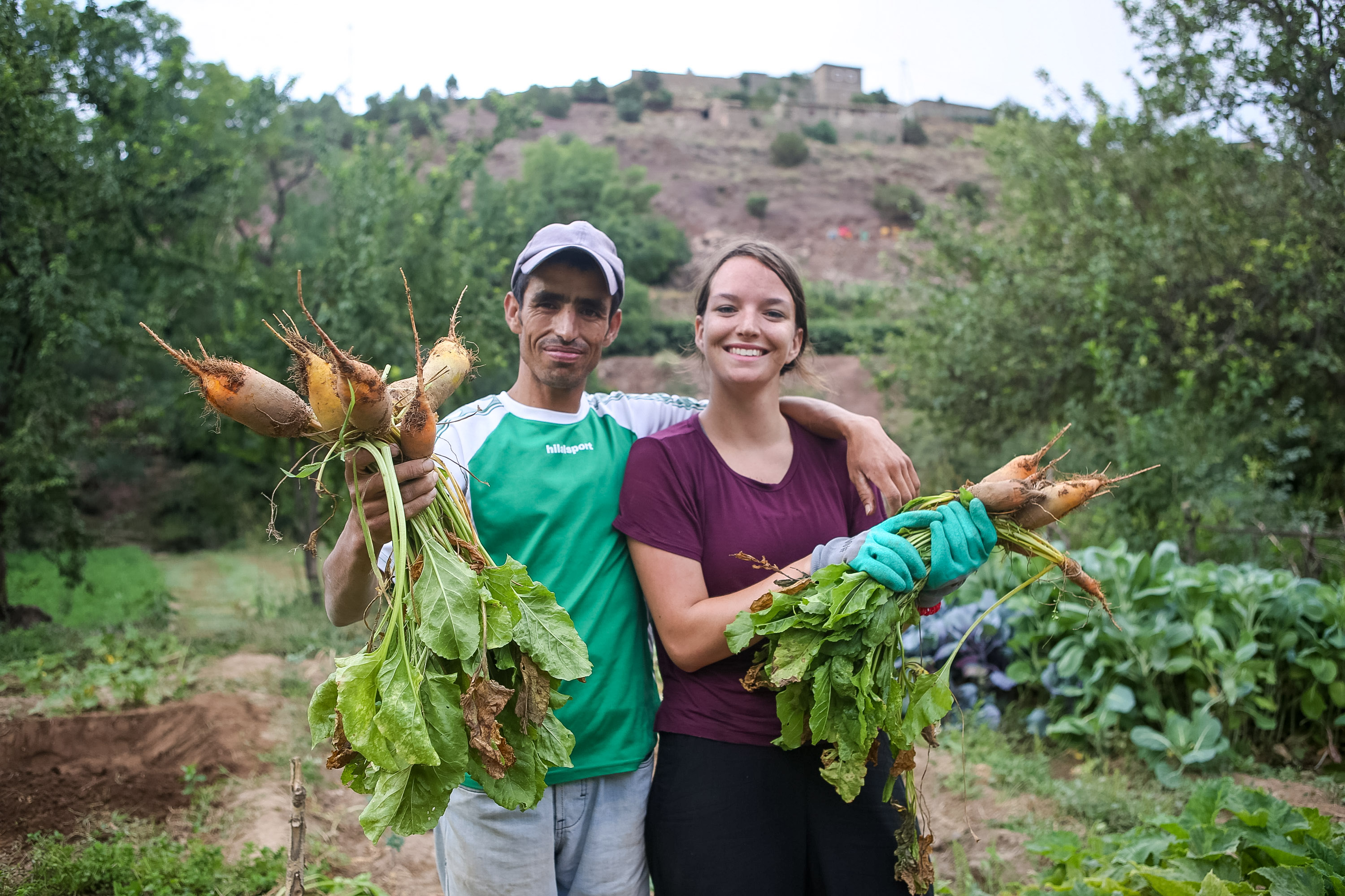 A local farmer and students hold freshly harvested beets in a mountain village garden