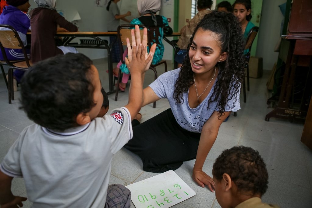 A student traveler giving a young boy a high five during an educational exchange on a language immersion teen tour.