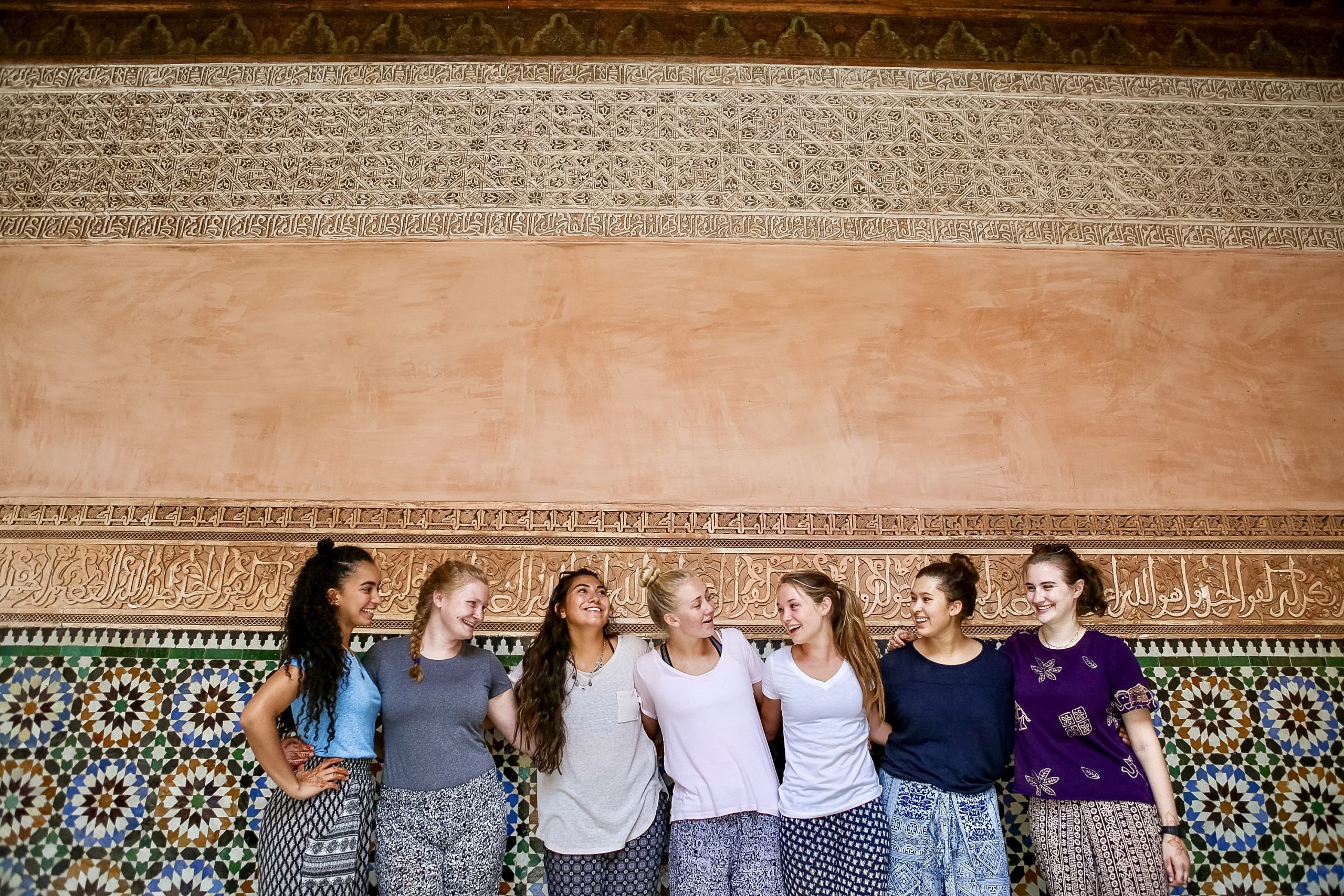 Students laugh together against an ornately tiled Moroccan wall