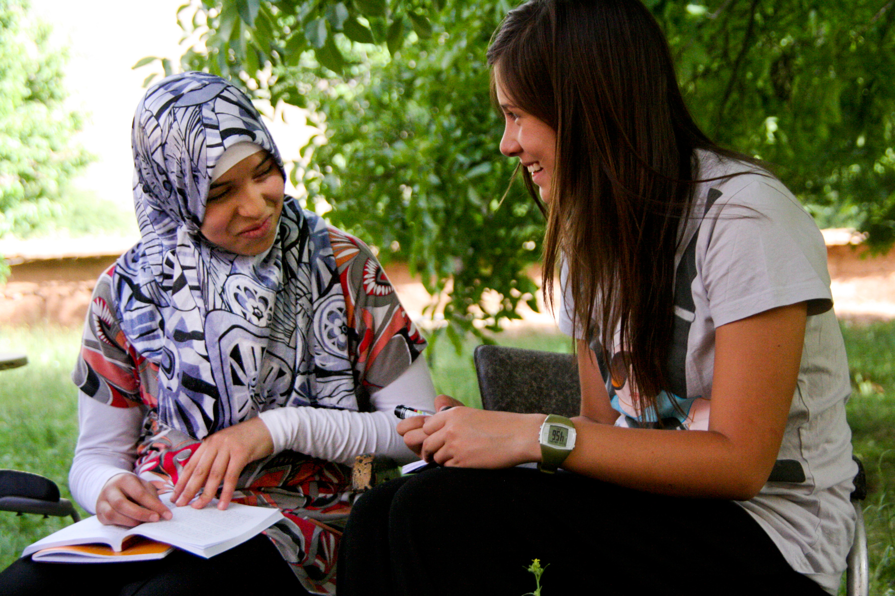 Students sit together outdoors writing in a notebook